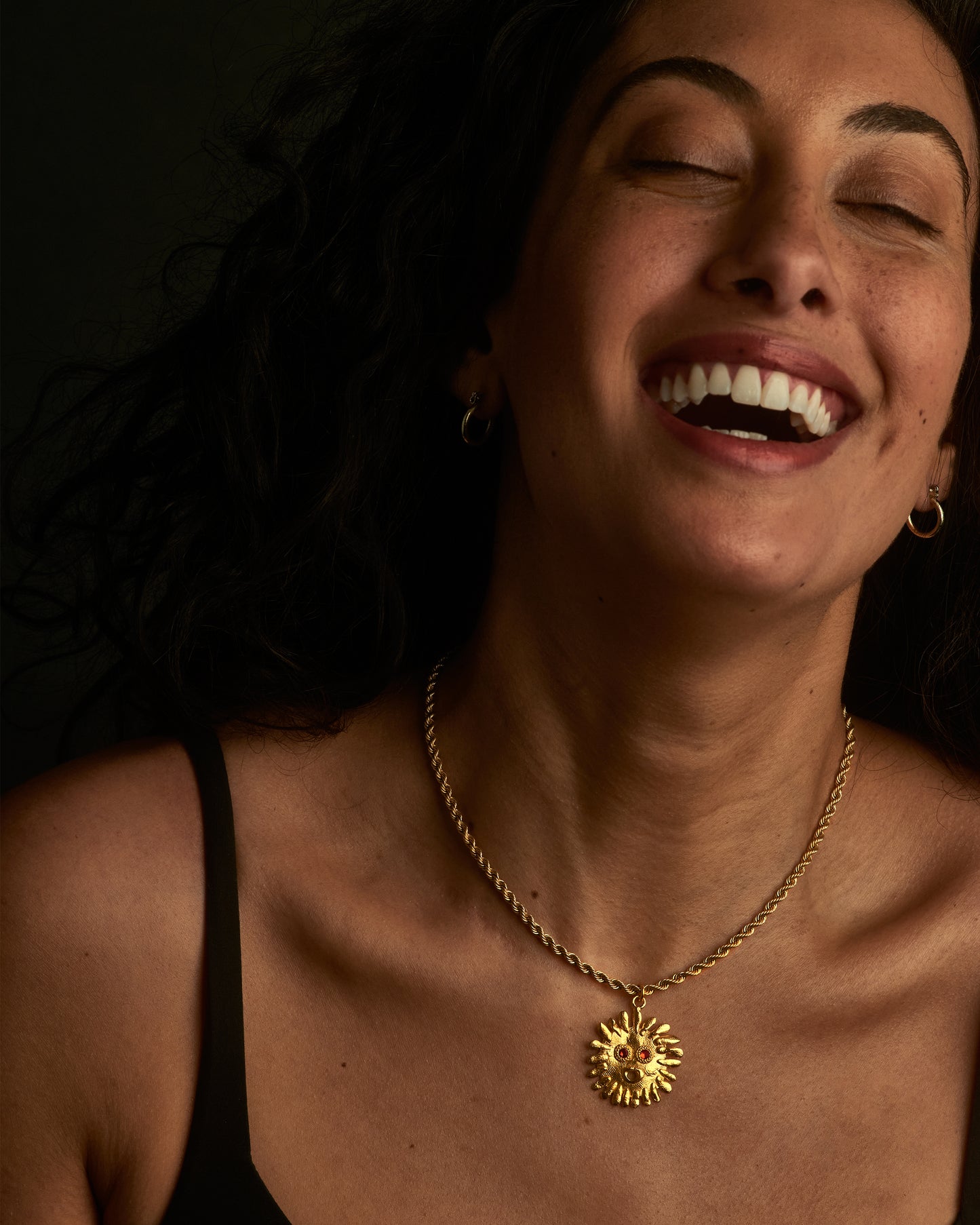 A handcrafted playful sun pendant with orange sapphire eyes.