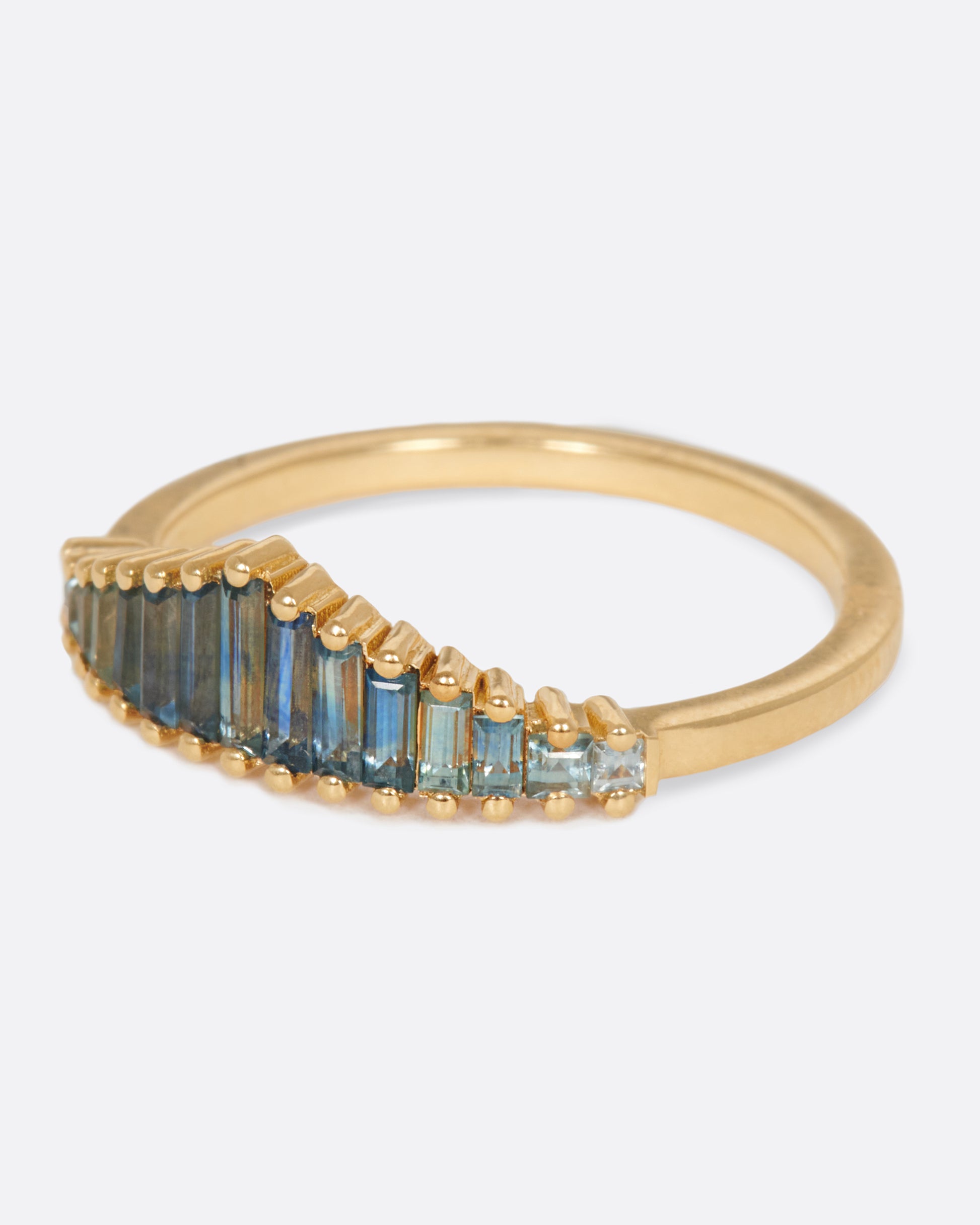 A crown ring covered in teal blue sapphire baguettes.