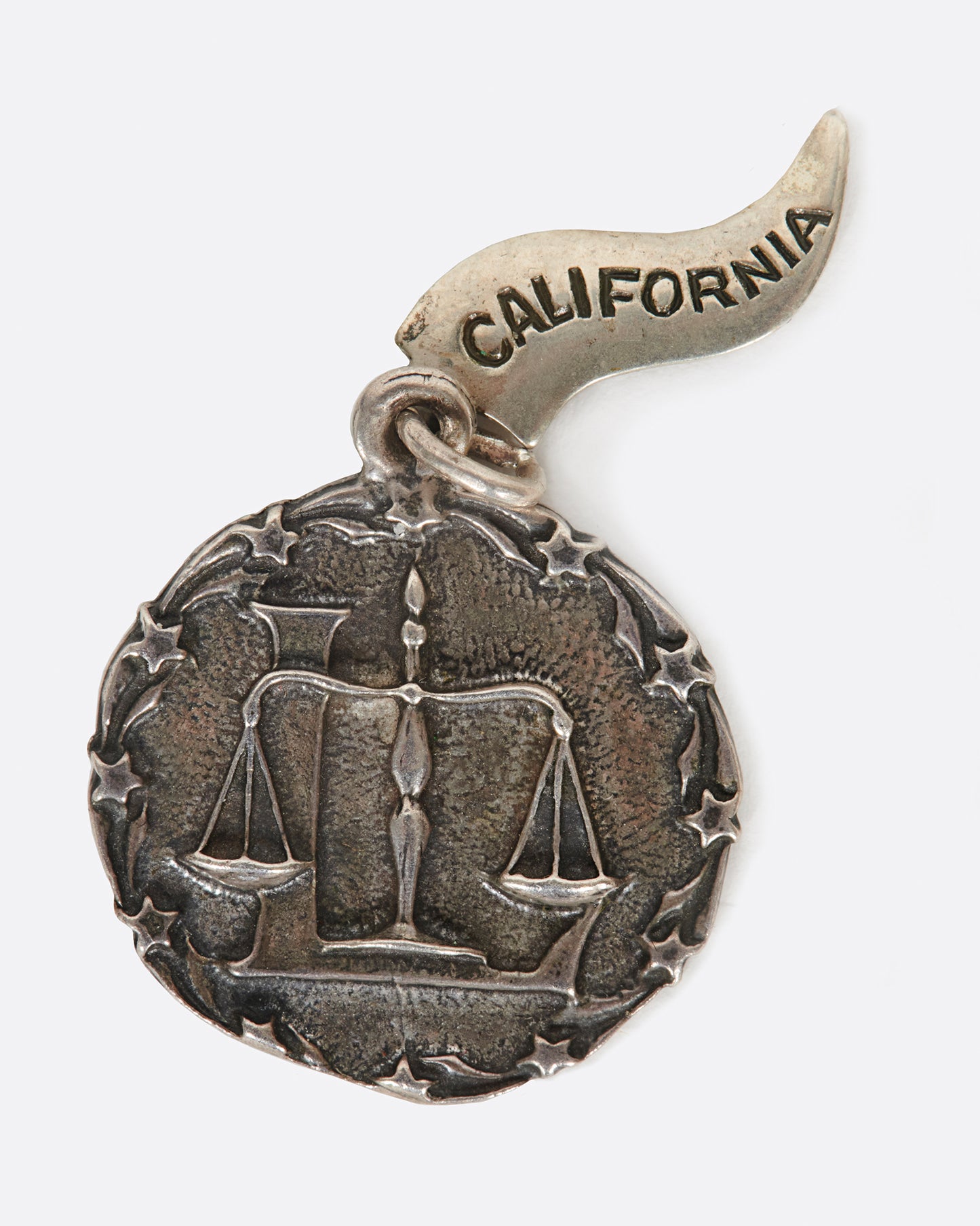 A round medal pendant with your zodiac sign and a California pennant.