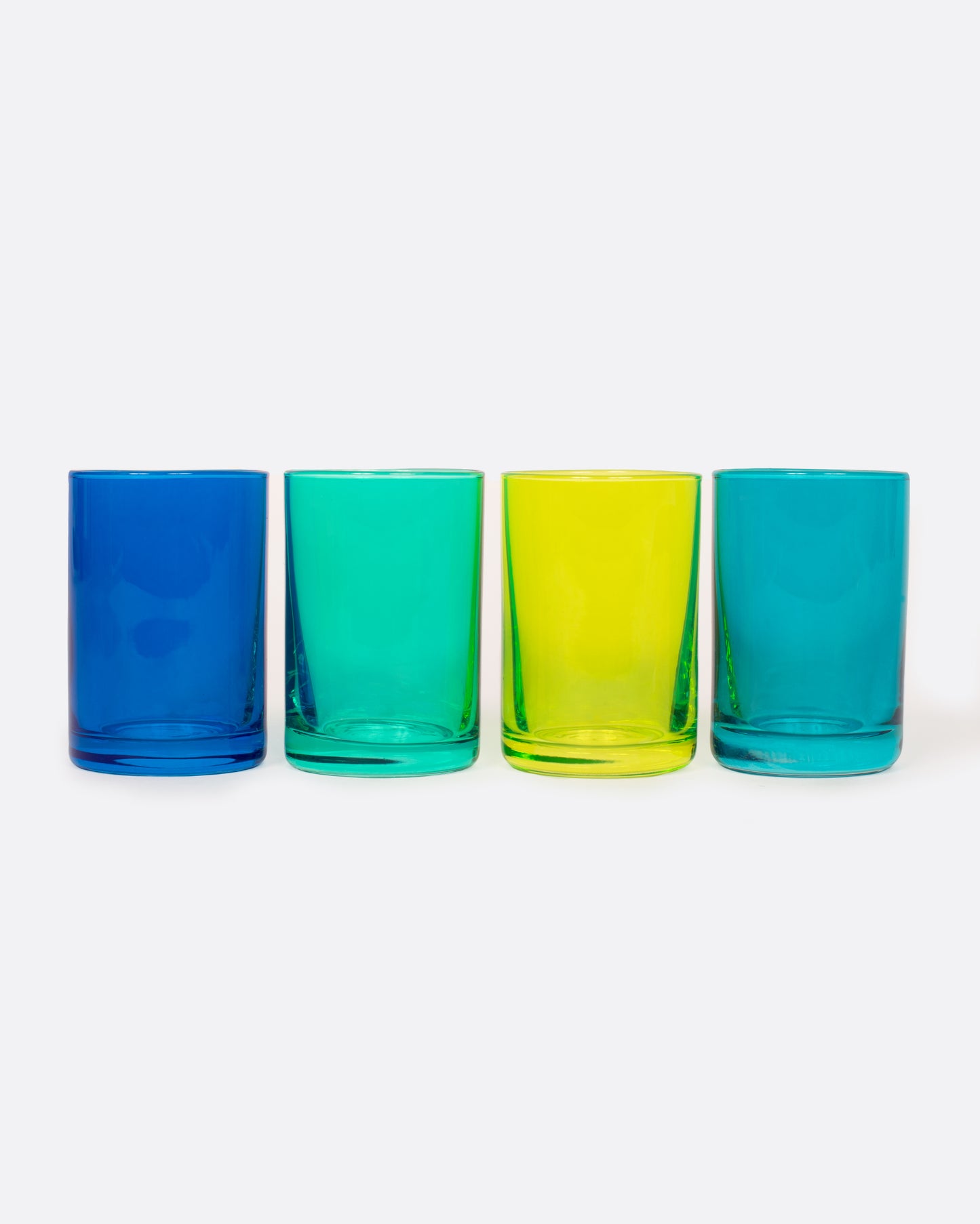 Four glass shot glasses in shades of green and blue. Shown from the front.