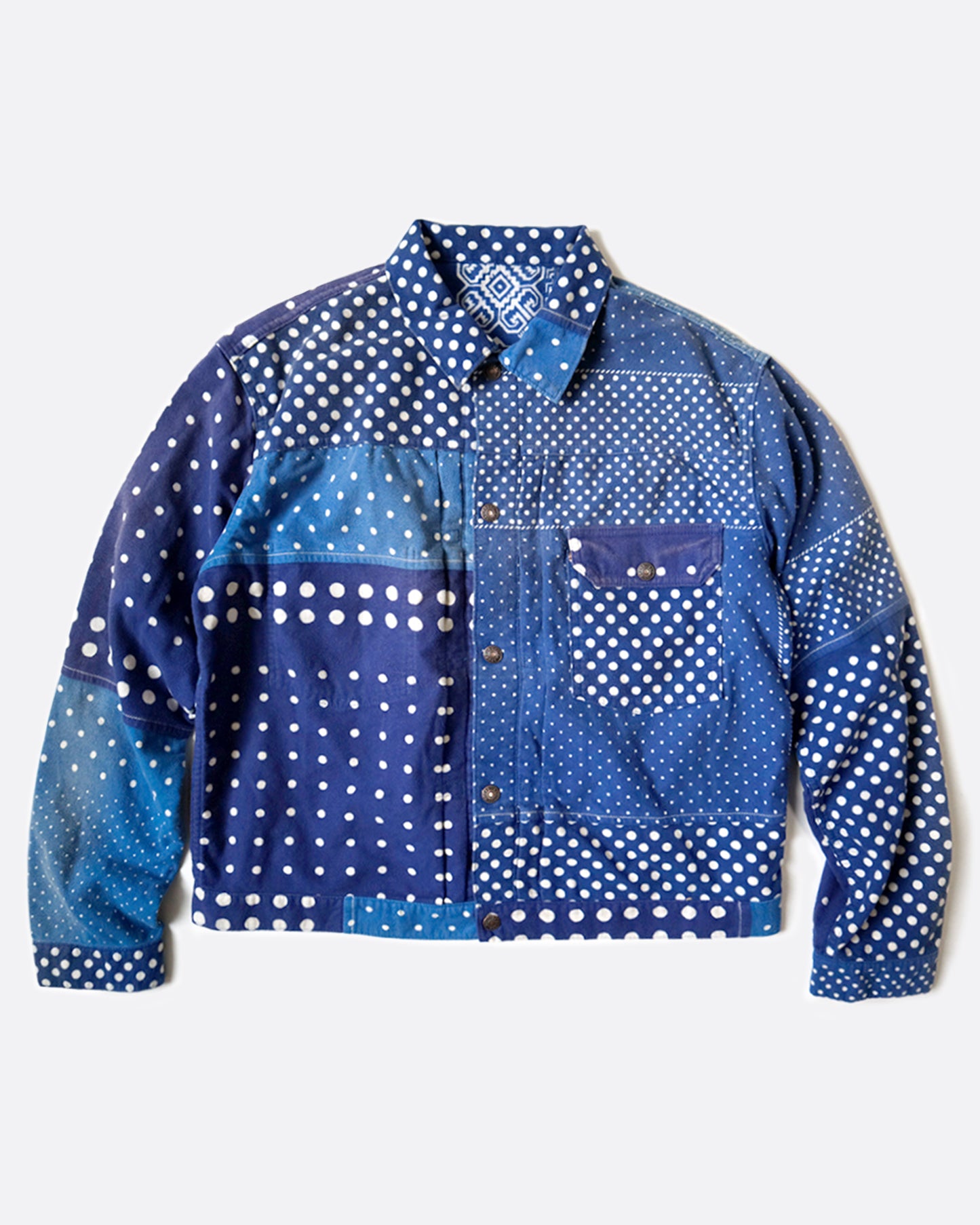 A blue flannel jacket in a patchwork polka dot pattern, shown lying flat from the front.