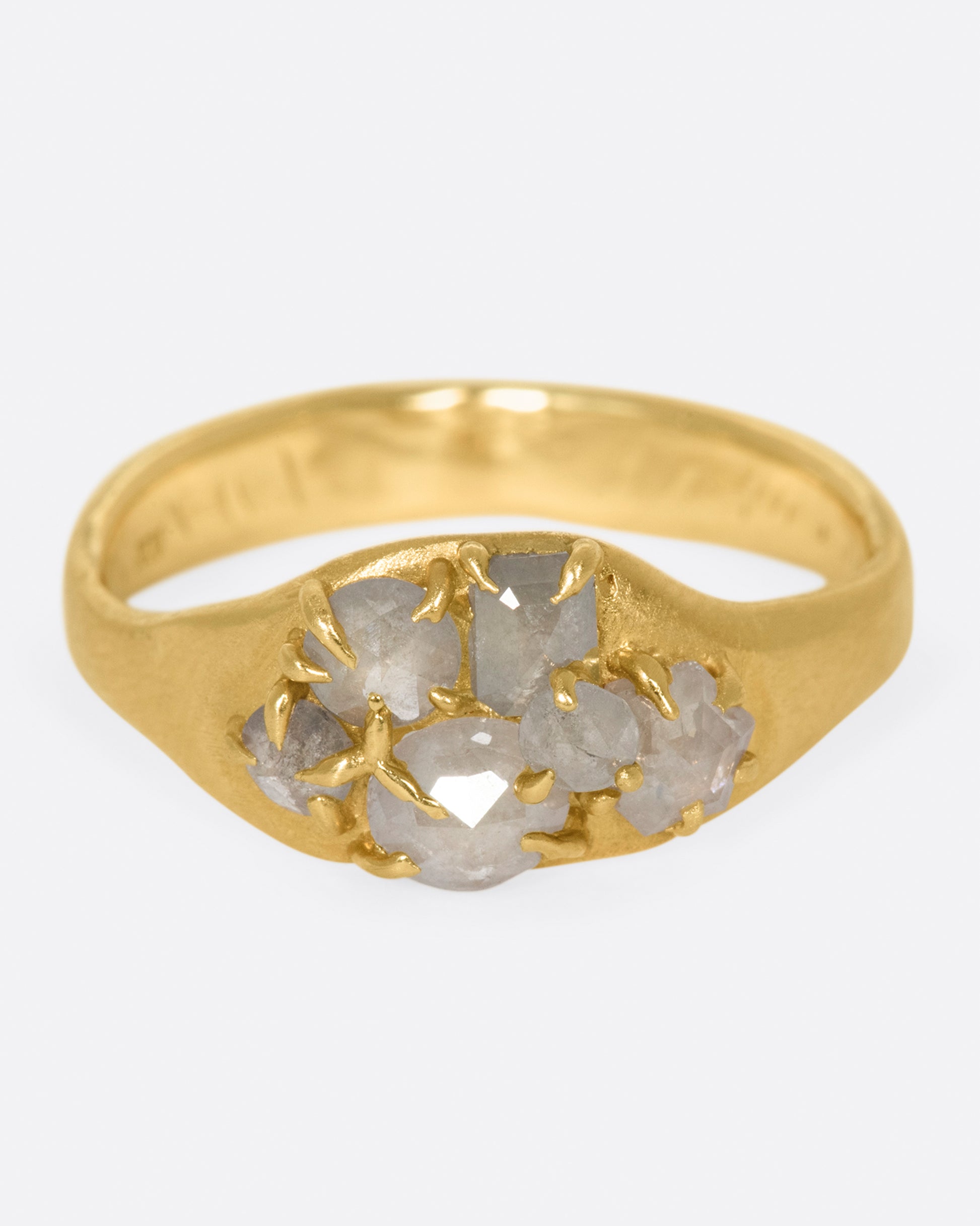 A yellow gold ring with a cluster of prong set gray diamonds on its face.