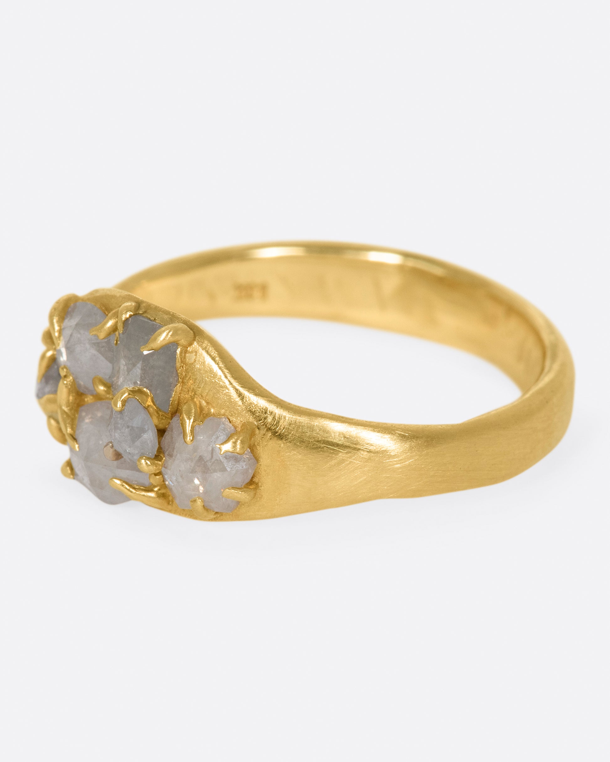 A yellow gold ring with a cluster of prong set gray diamonds on its face.