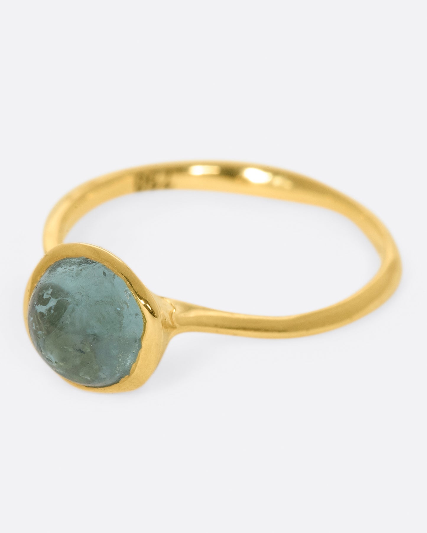 A wonky gold ring with a blue tourmaline cabochon set atop it.