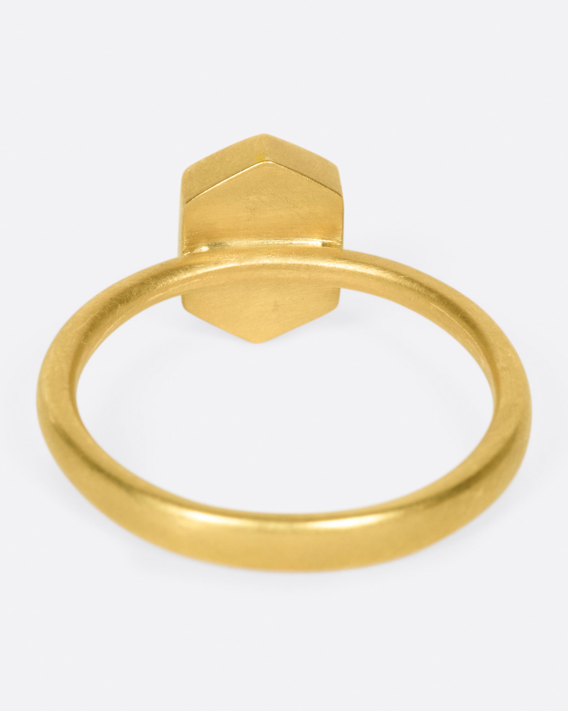 A yellow gold ring with a salt and pepper hexagonal diamond. Shown from the back.