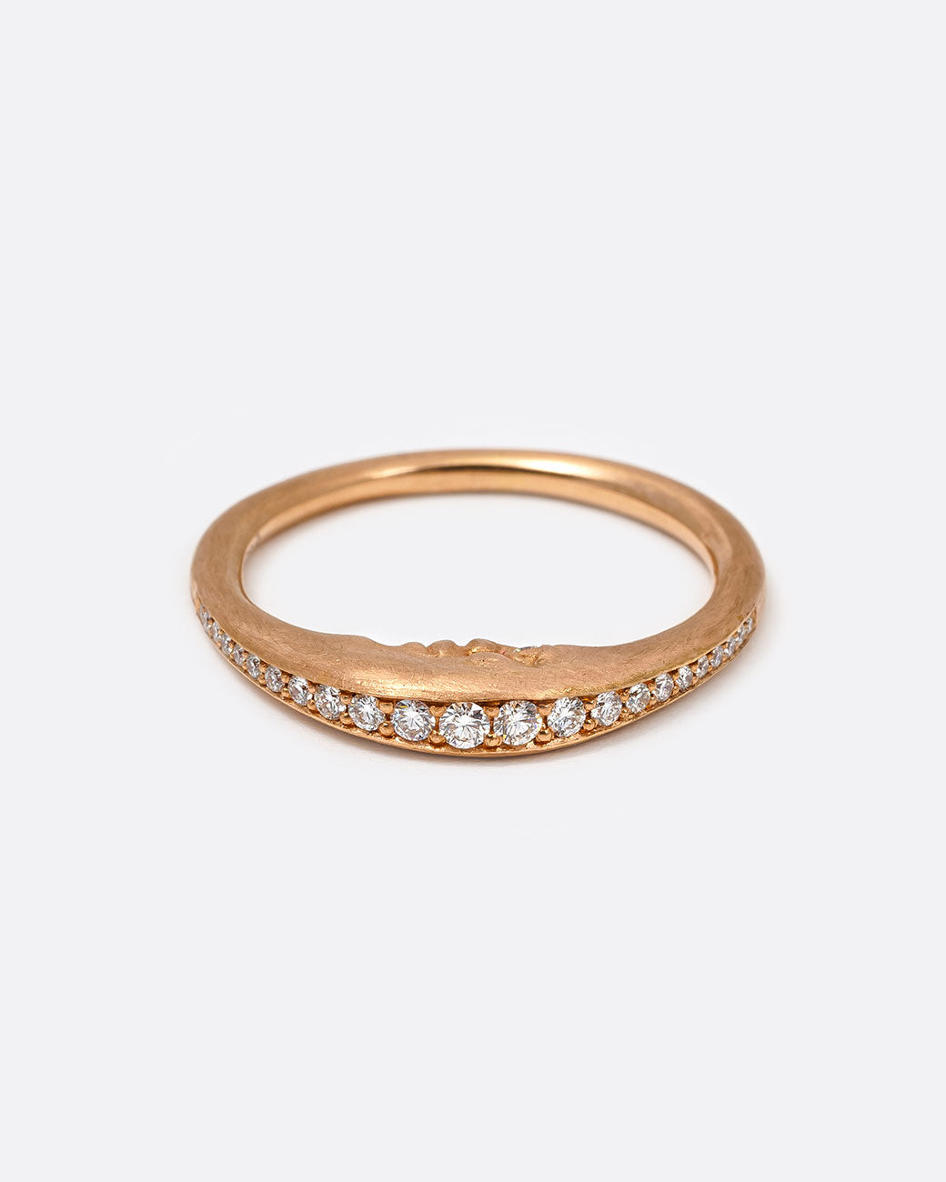A rose gold crescent moon ring with a diamond eyed face and graduated white diamonds around the top edge. Shown lying flat from the front.