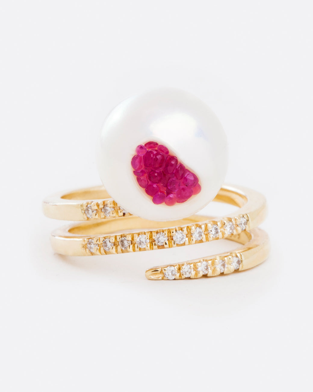 A yellow gold wrap ring with an organic freshwater pearl lined with rubies. Shown from the front.