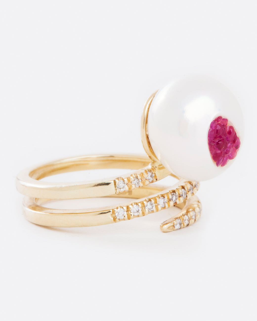 A yellow gold wrap ring with an organic freshwater pearl lined with rubies. Shown from the side.