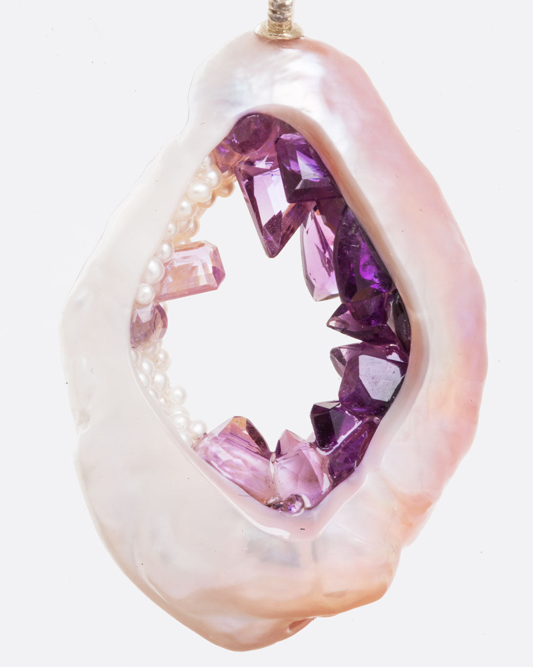 A large soufflé pearl open in the center and filled with pearls and amethysts. Shown from the front.