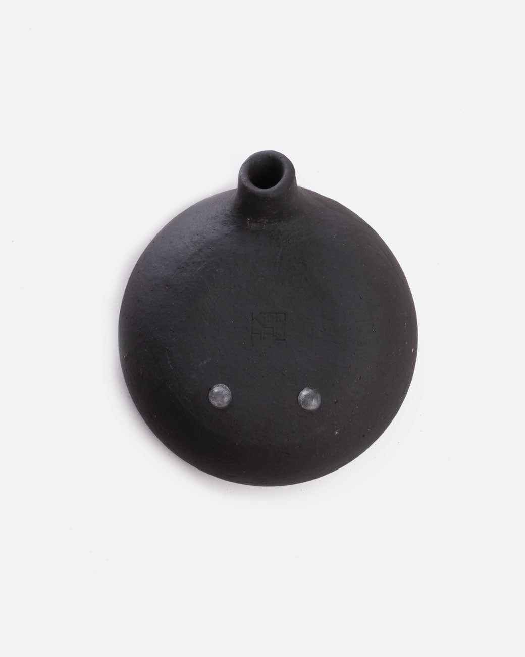 A black stoneware soap dish with a drainage spout. Shown from the bottom.