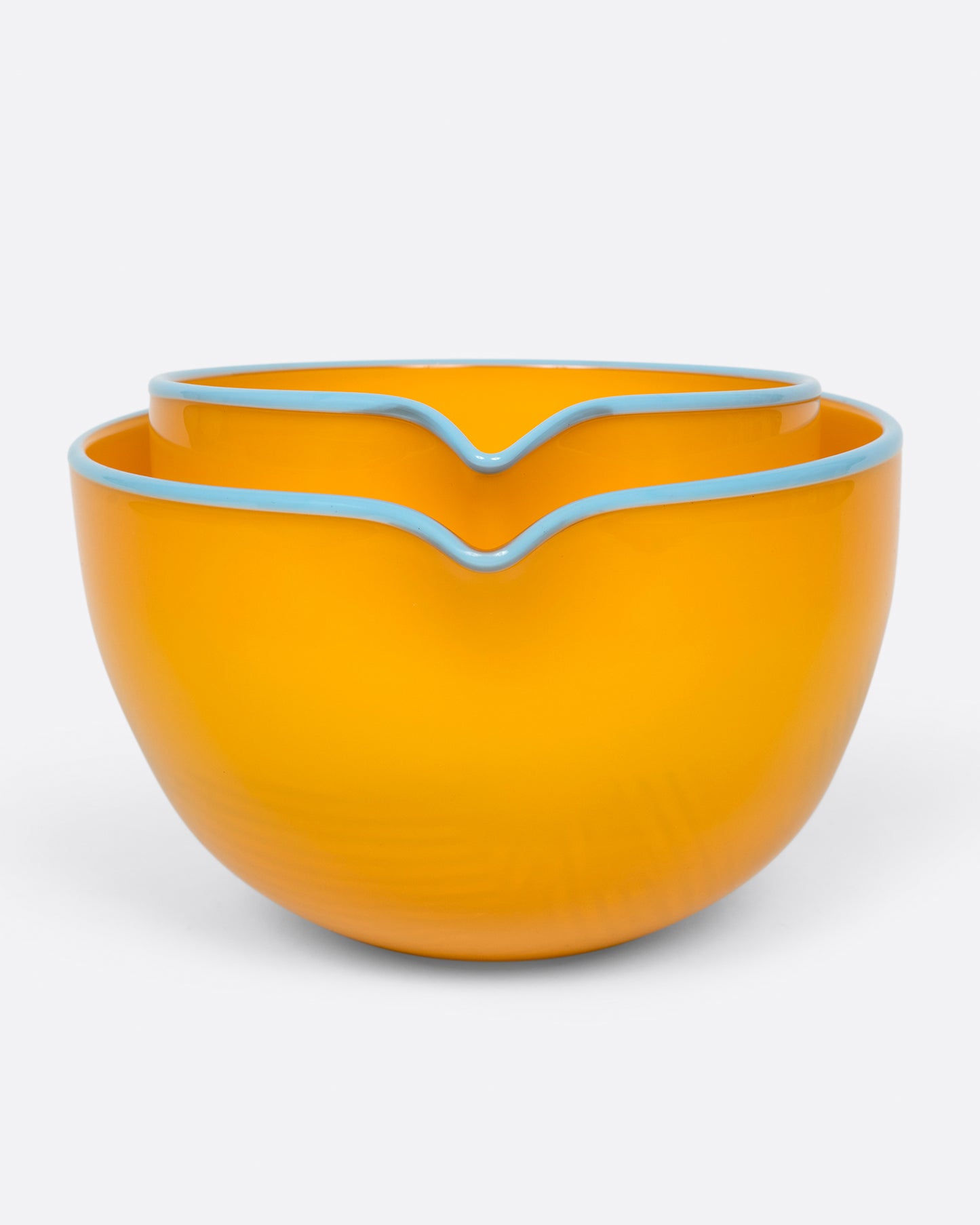 A small marigold spouted glass bowl stacked inside a large marigold spouted bowl. Shown from the front.