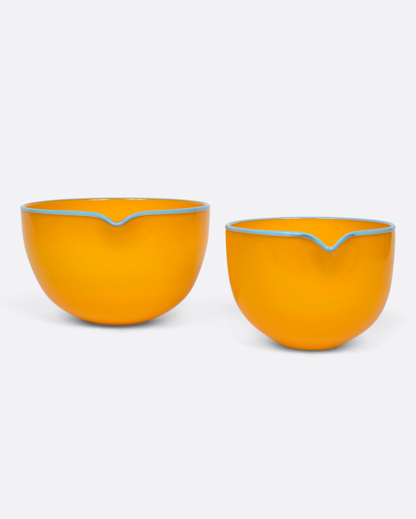 A small marigold spouted glass bowl next to a large marigold spouted bowl. Shown from the front.