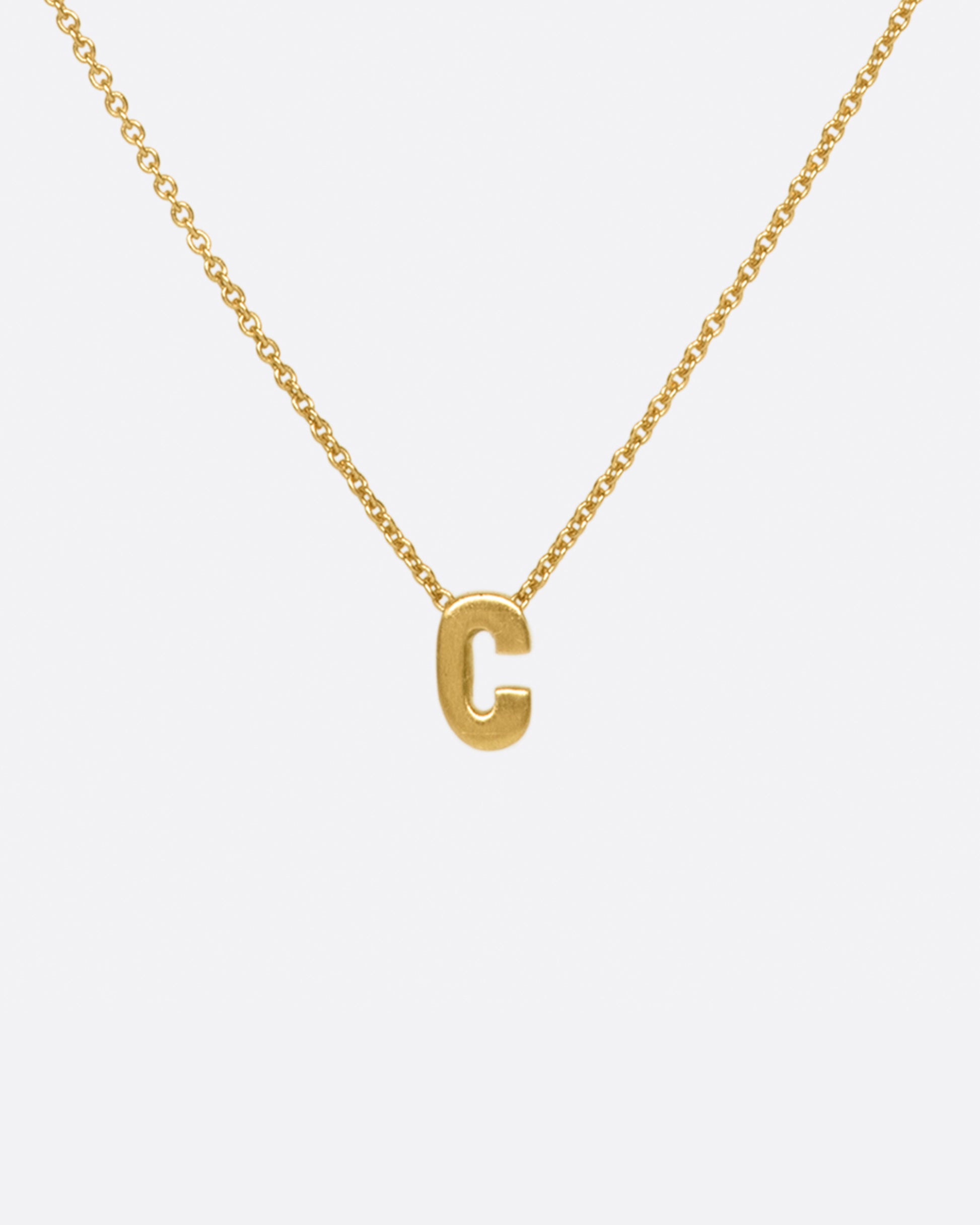 A yellow gold cable chain necklace with a letter C initial pendant. Shown from the front.