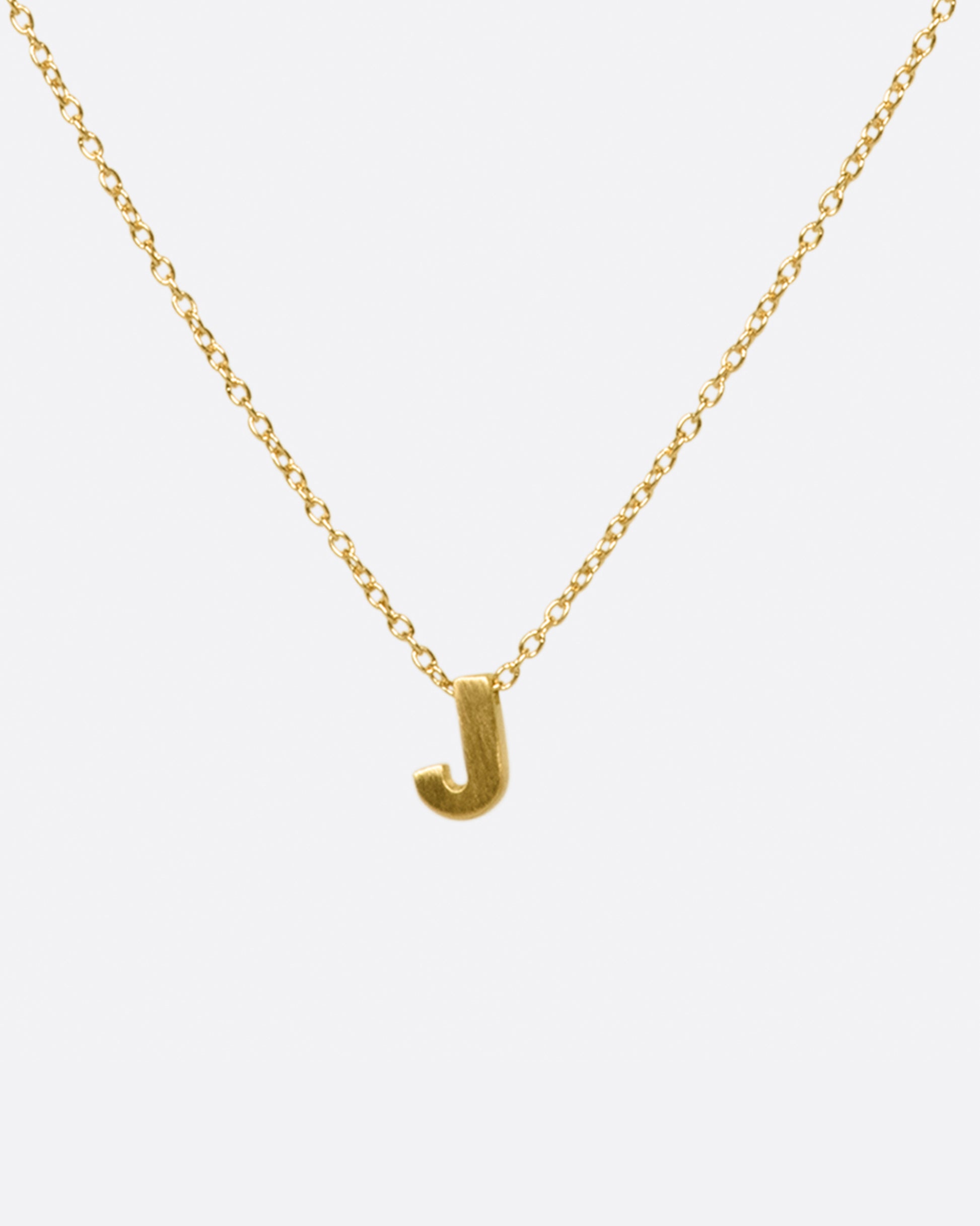 A yellow gold cable chain necklace with a letter J initial pendant. Shown from the front.