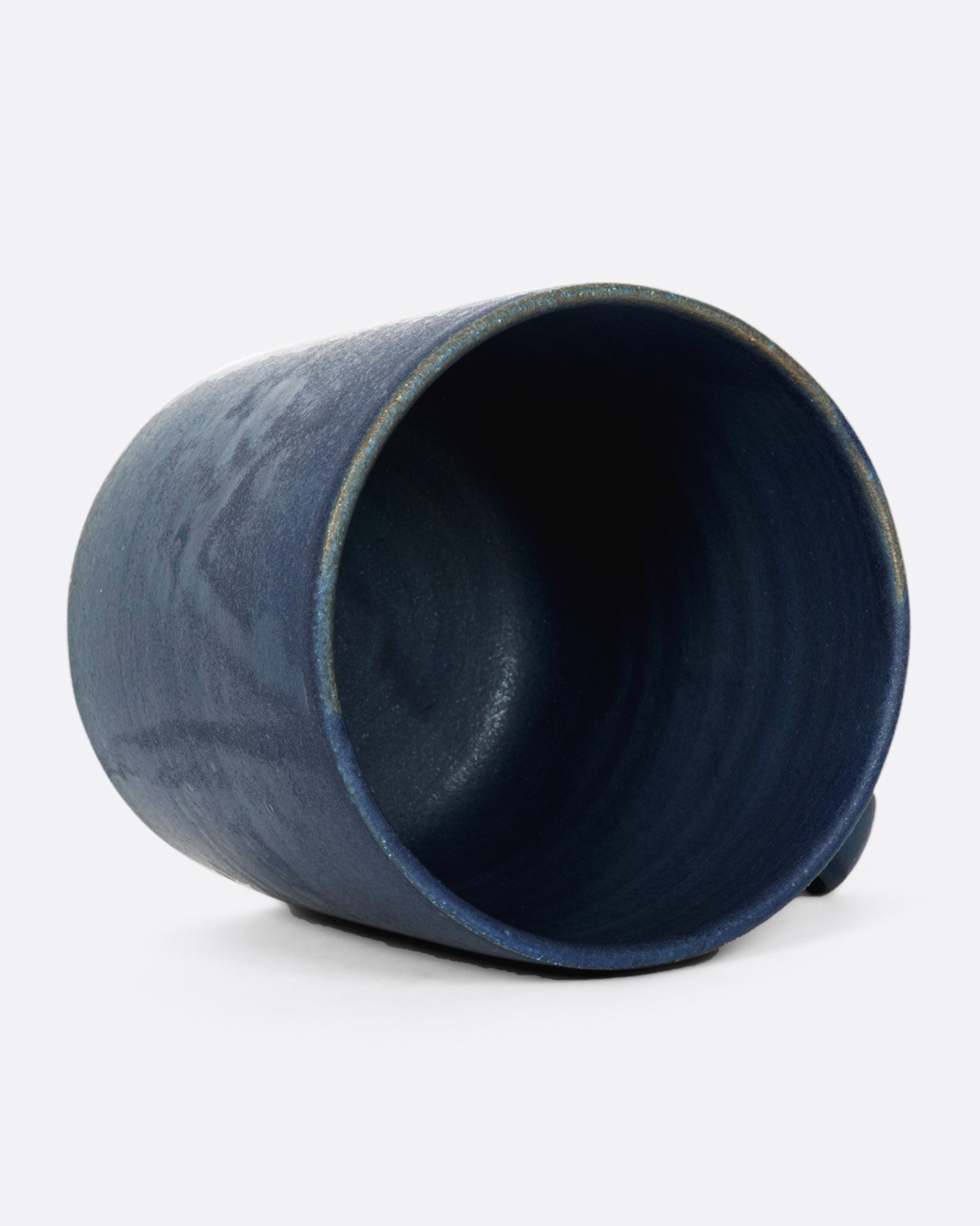 A hand thrown ceramic mug with a matte, deep blue glaze.