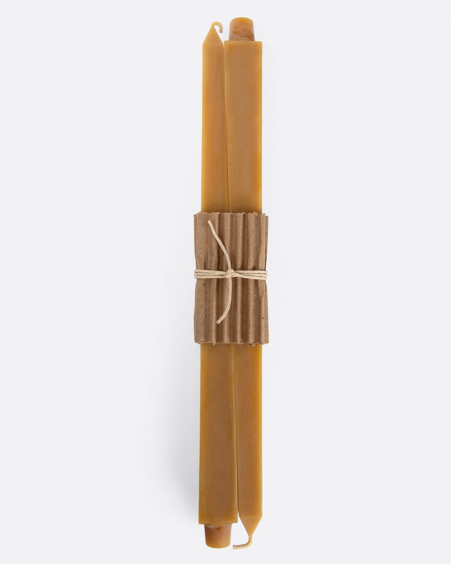 Gold square taper candles lying flat with cardboard wrapping at the center. Shown from the front.