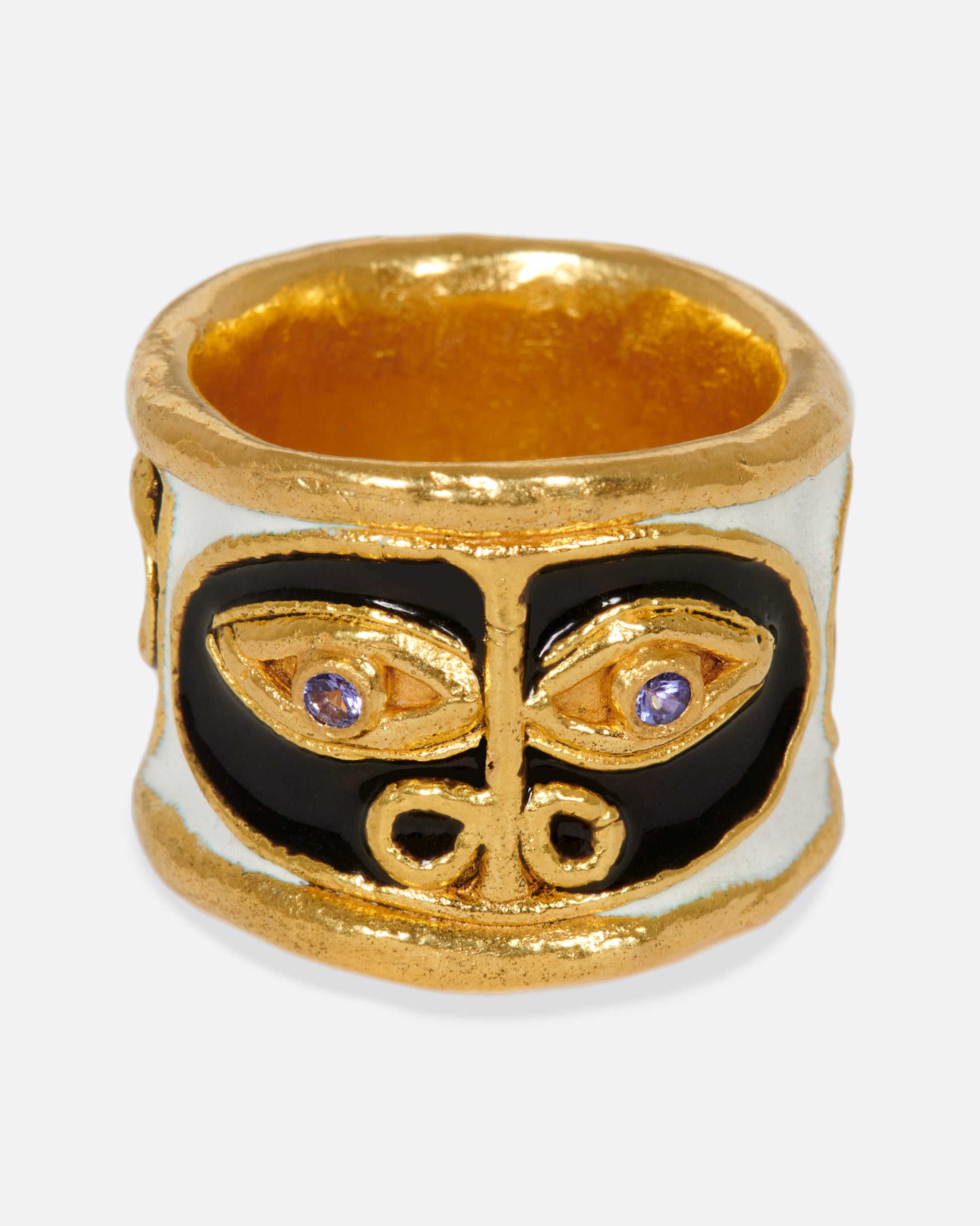 A handcrafted, high karat gold band with three faces illuminated by black and white enamel, and brightly colored stone eyes.