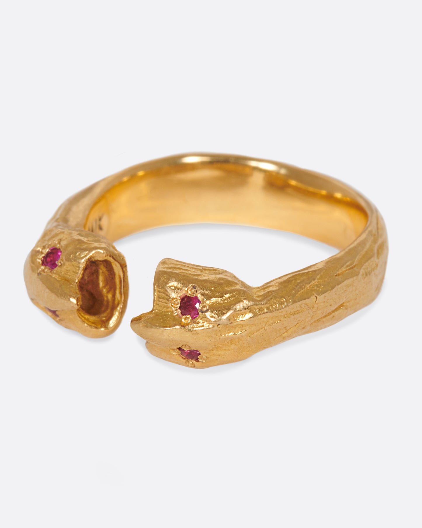 A yellow gold open ring with two ruby eyed faces facing each other. Shown from the side.