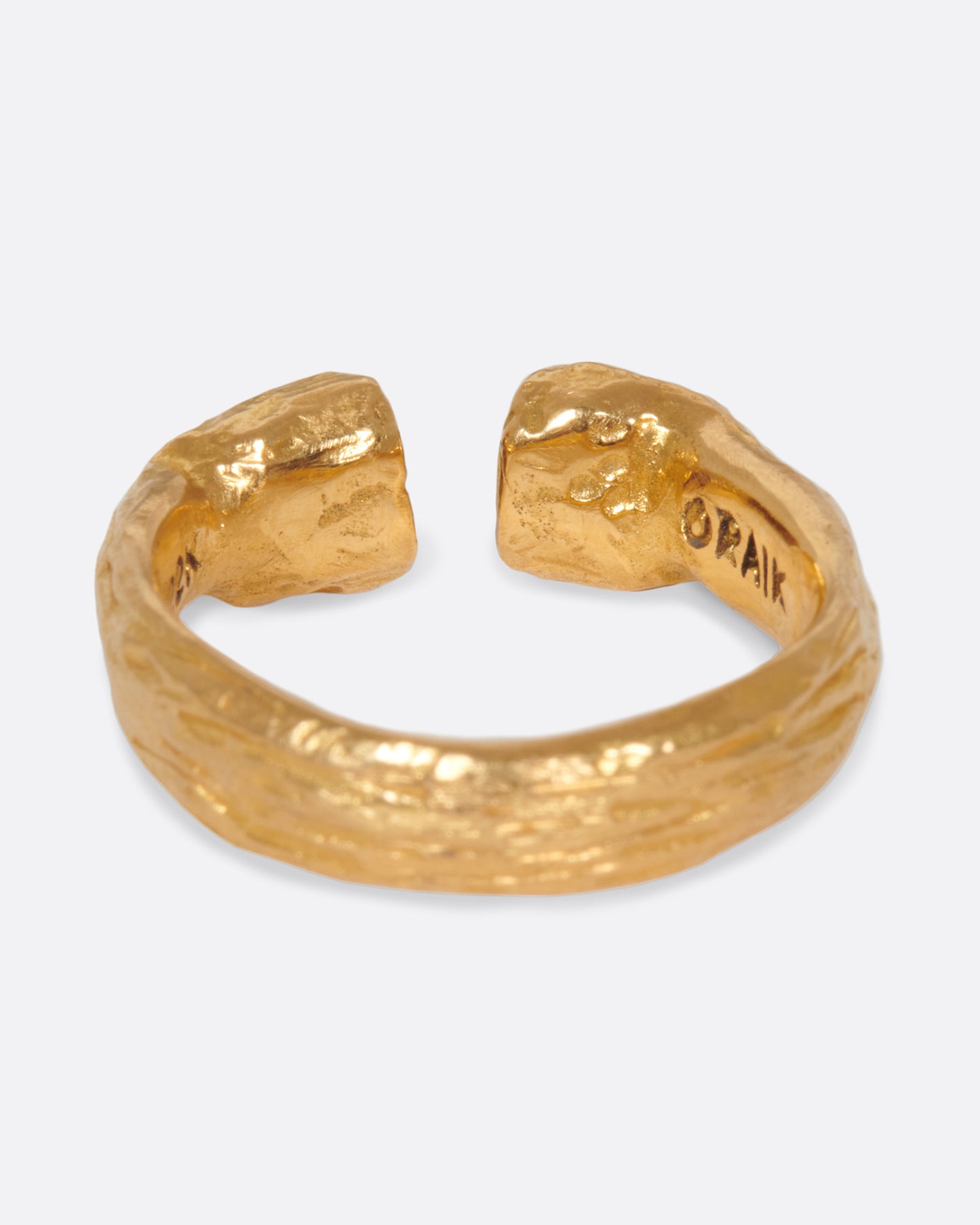 A yellow gold open ring with two ruby eyed faces facing each other. Shown from the back.