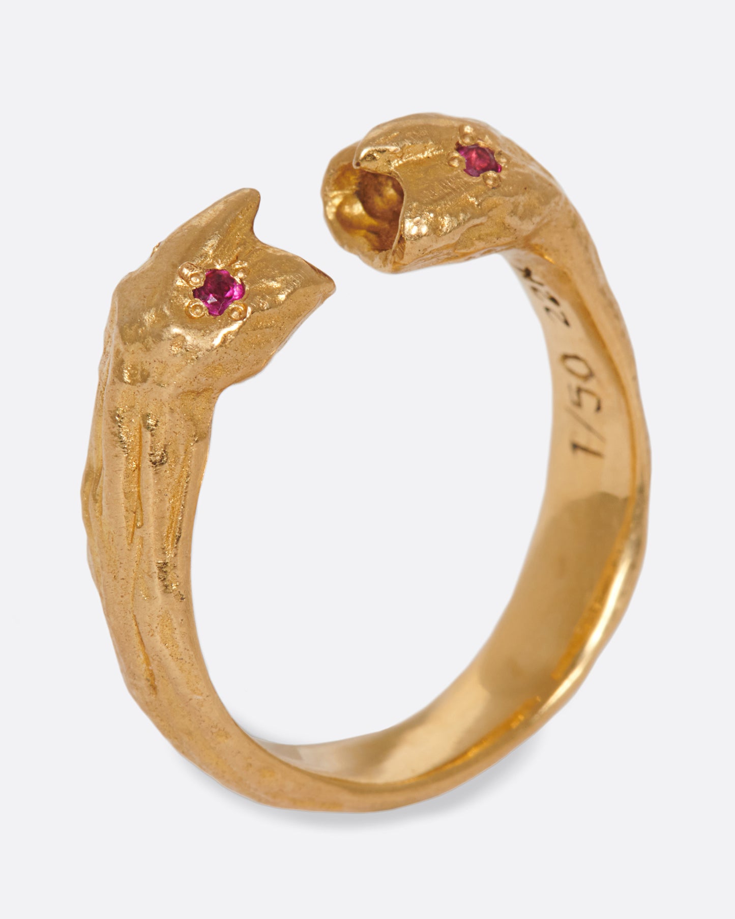 A yellow gold open ring with two ruby eyed faces facing each other. Shown standing up from the side.