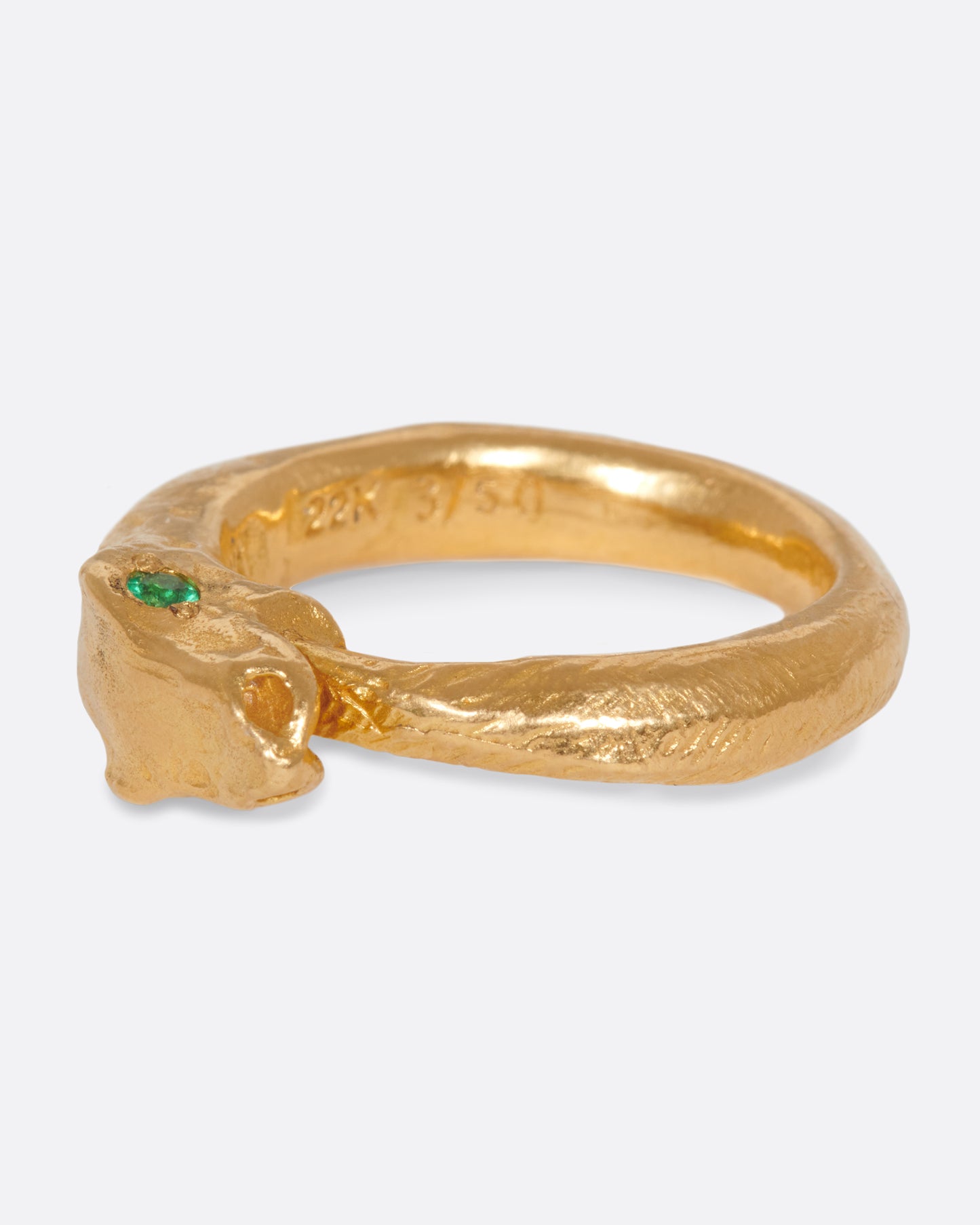 A yellow gold ouroboros ring with a emerald eyed serpent catching its own tail. Shown from the side.