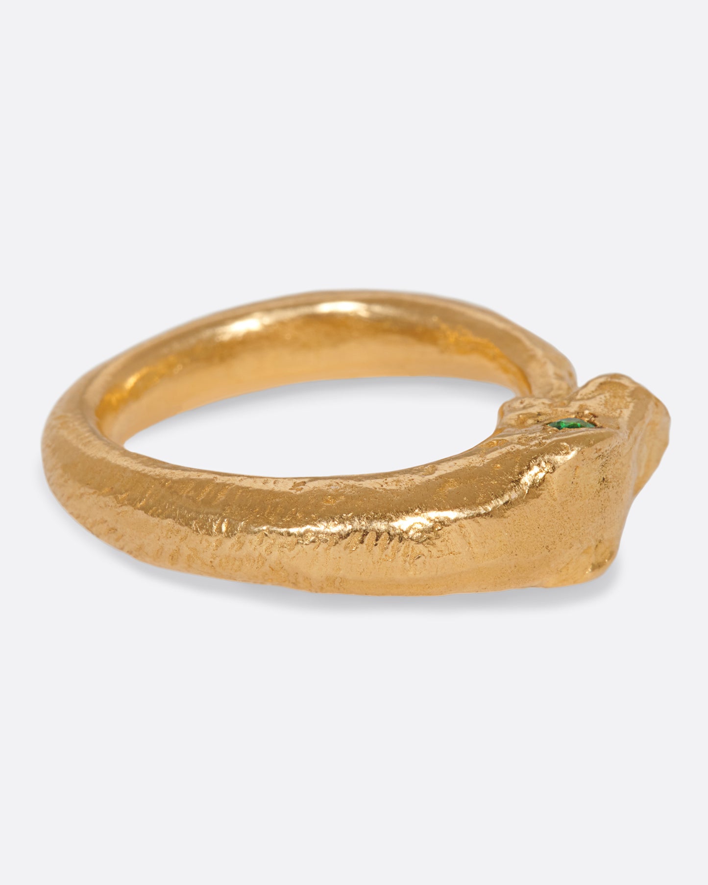 A yellow gold ouroboros ring with a emerald eyed serpent catching its own tail. Shown from the side.