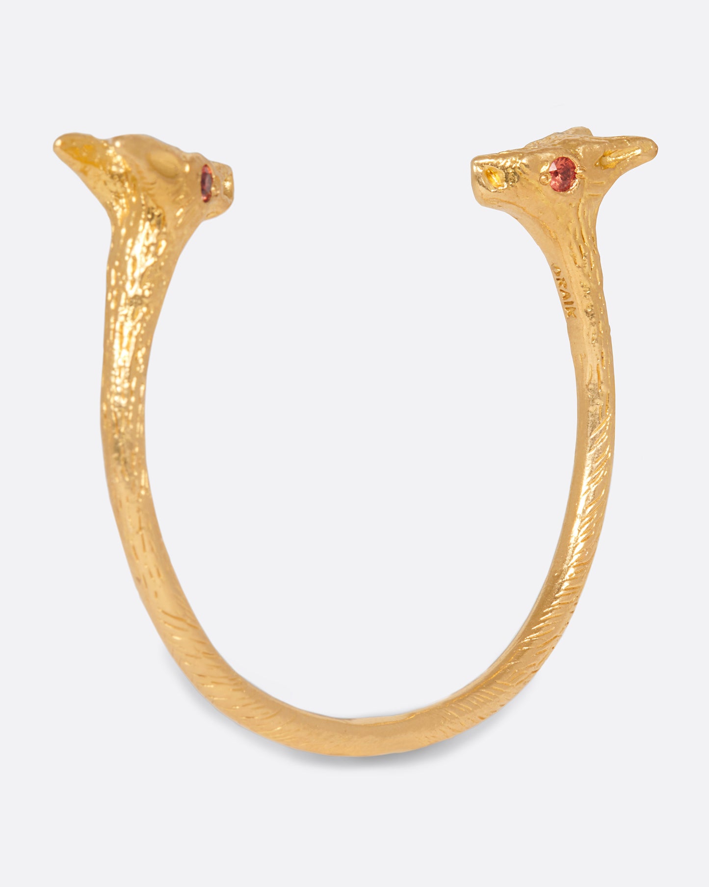 A solid 22k gold cuff bracelet with a fox at either end, accented by orange sapphire eyes.