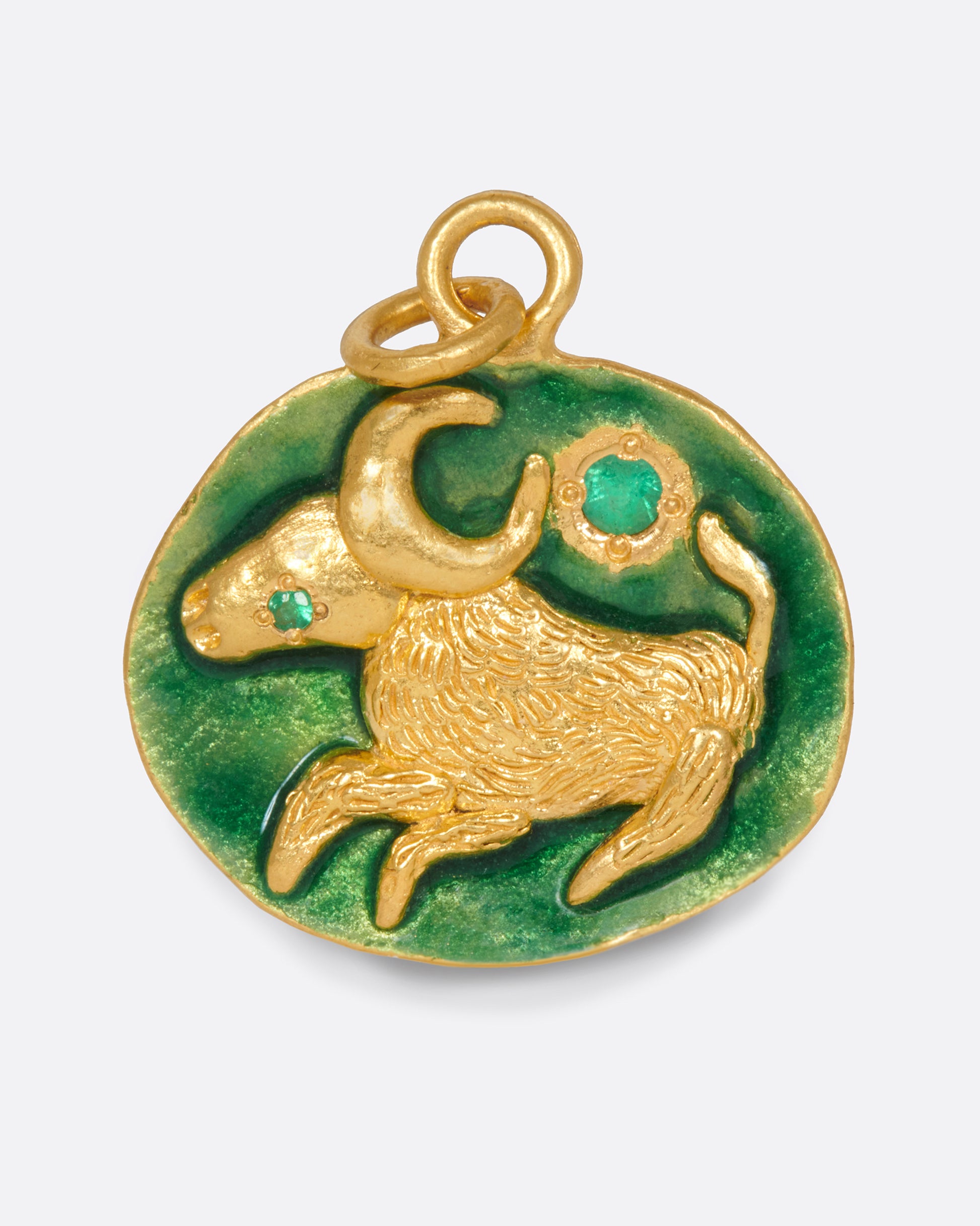 A slightly asymmetrical, circular pendant with a Taurus bull and emerald accents.