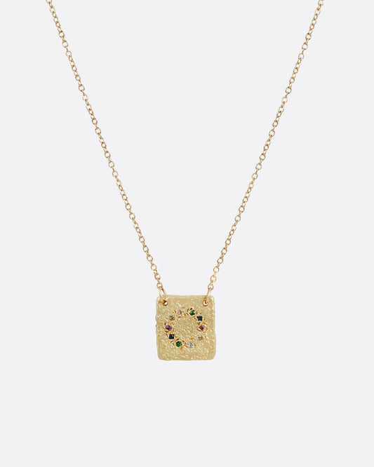 A textured 14k yellow gold square pendant with a circle of stones including amethyst, emerald, aquamarine and multicolor sapphires hanging on a cable chain.