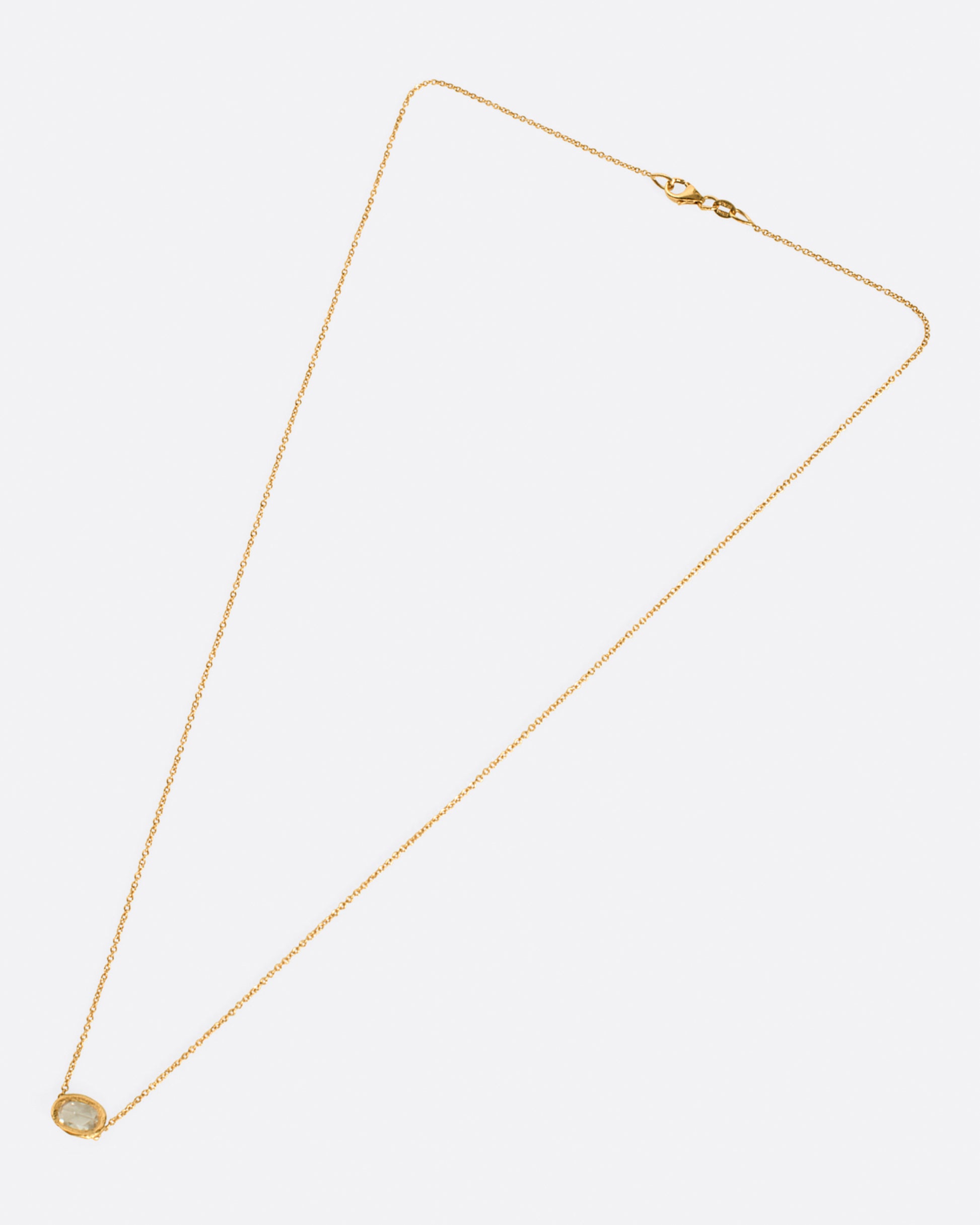 A rose gold hand carved bezel pendant containing an east-west rose cut diamond on a cable chain. Shown from the front.