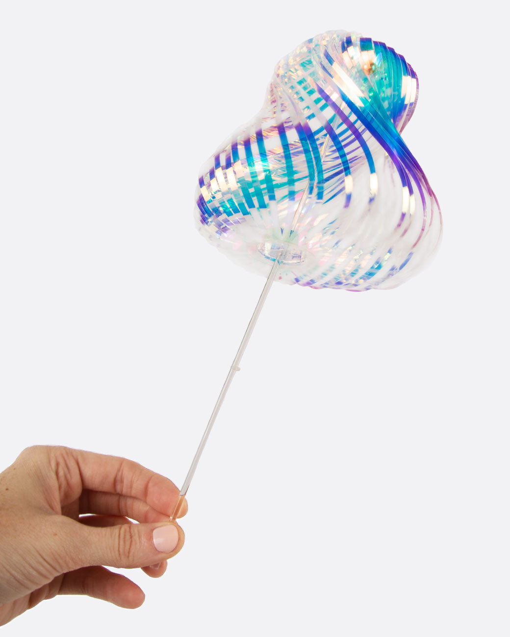 A plastic rainbow stick with an iridescent sheen. Shown being held by a hand.