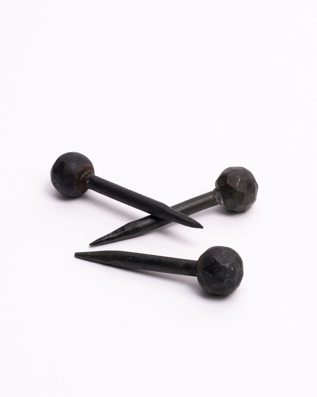 A group of three round head iron nails. Shown lying on their sides.