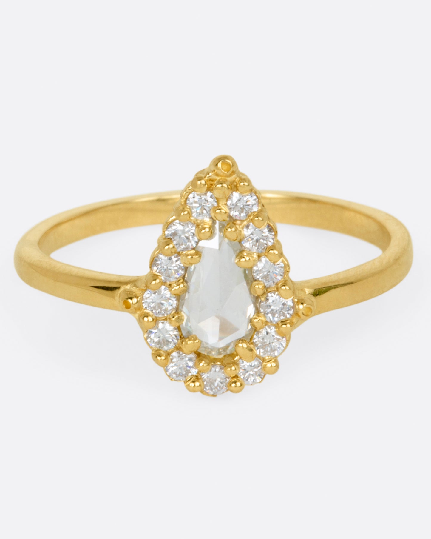 A yellow gold ring with a light champagne rose cut pear shaped diamond haloed by round diamonds. Shown from the front.