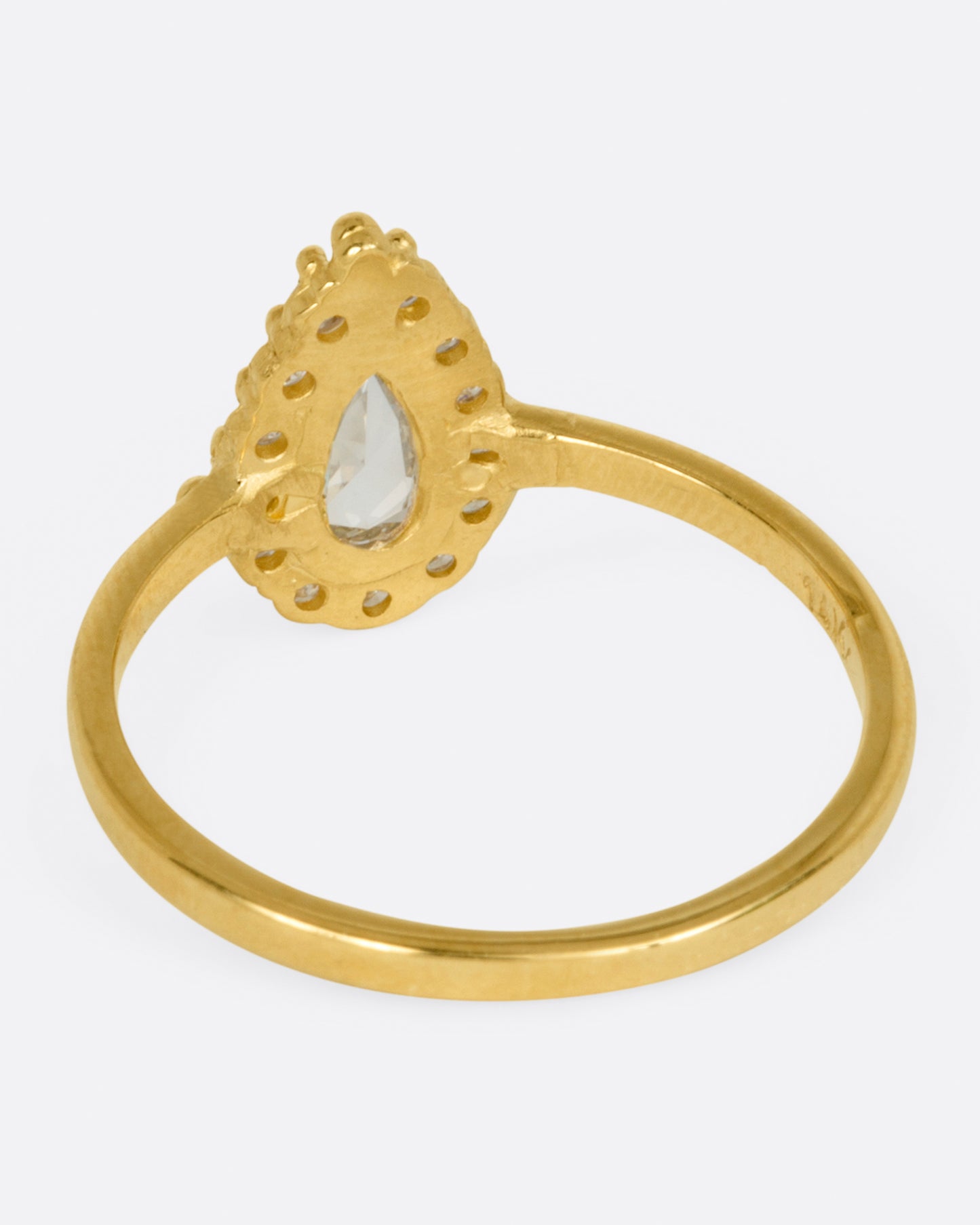 A yellow gold ring with a light champagne rose cut pear shaped diamond haloed by round diamonds. Shown from the back.