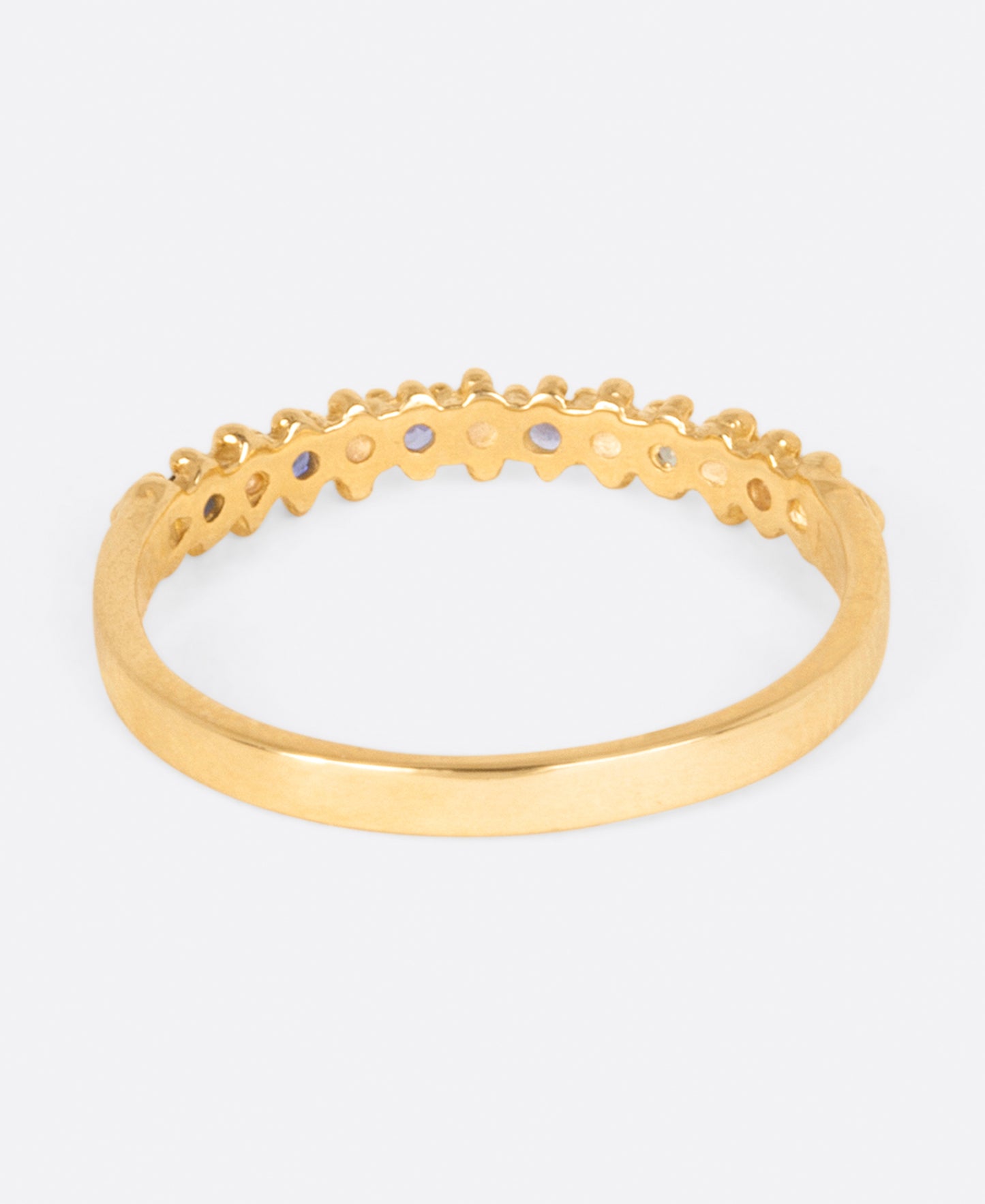 A textured yellow gold band with an ombré queue of six sapphires shown from the back.