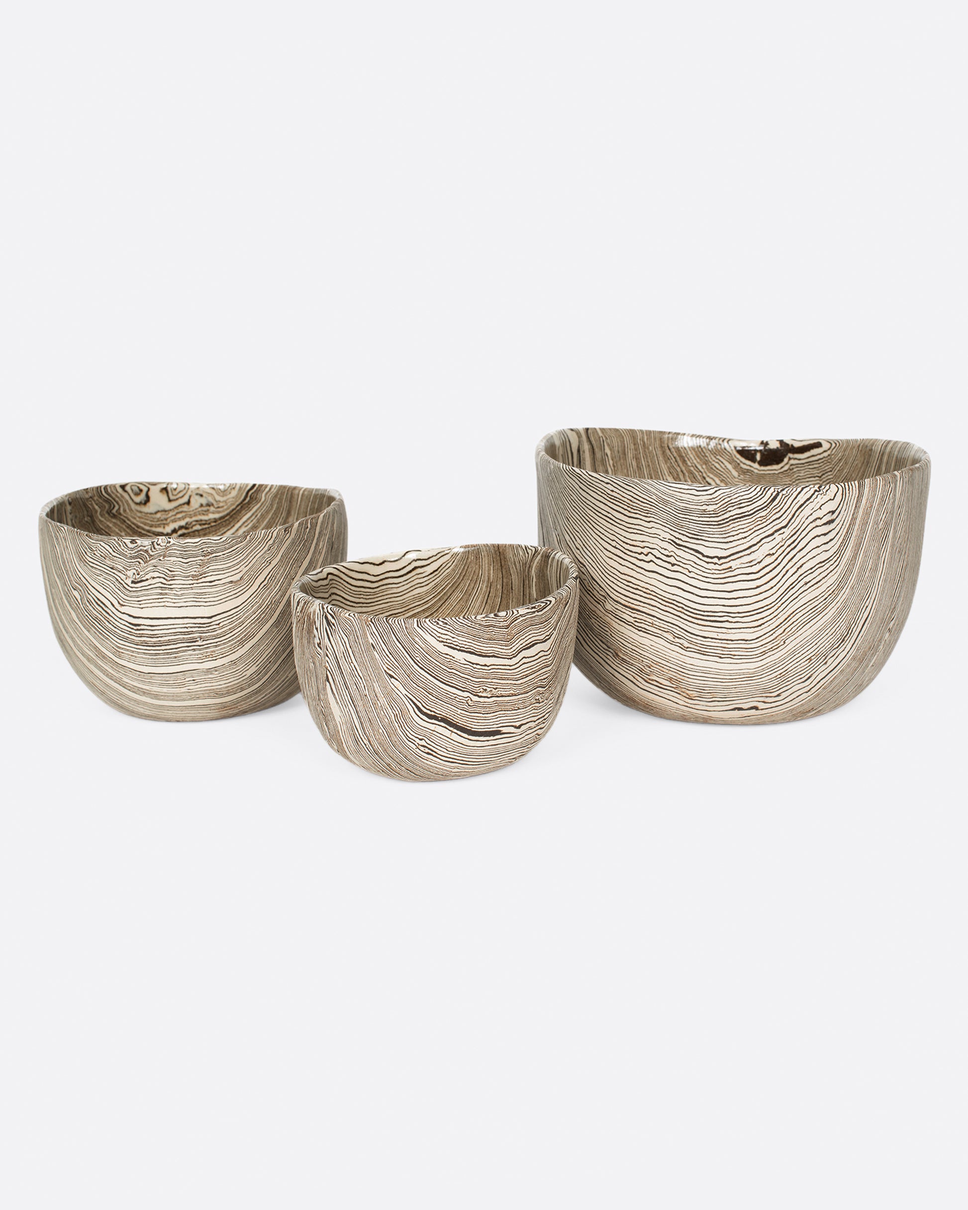 A group of three white and brown stoneware nerikomi bowls. Shown from the front.