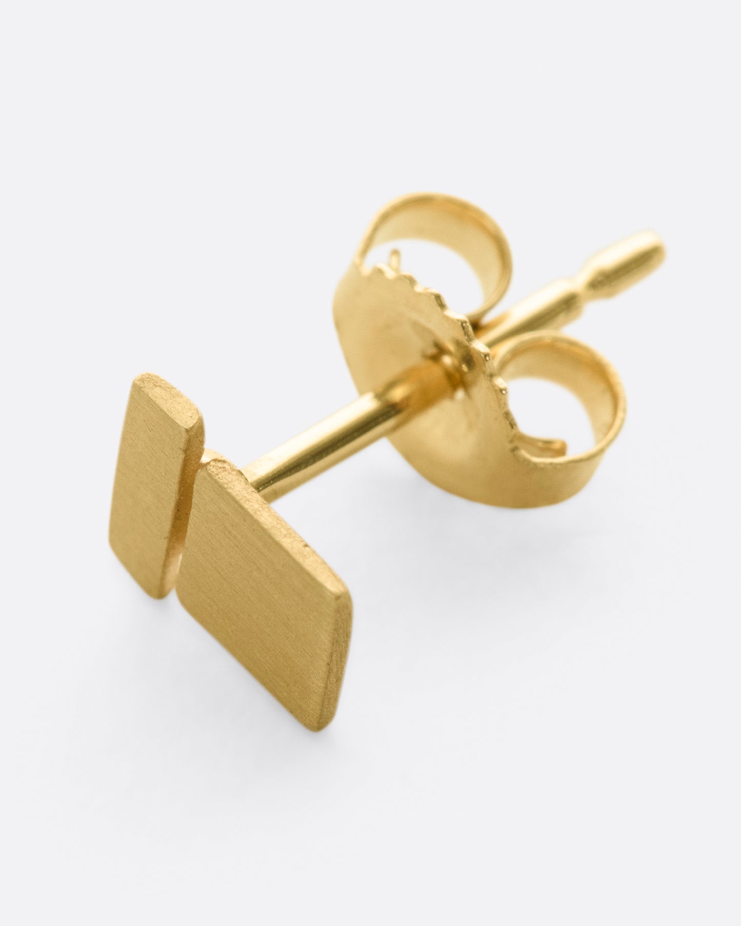 A yellow gold stacked geometric stud earring with matte finish.