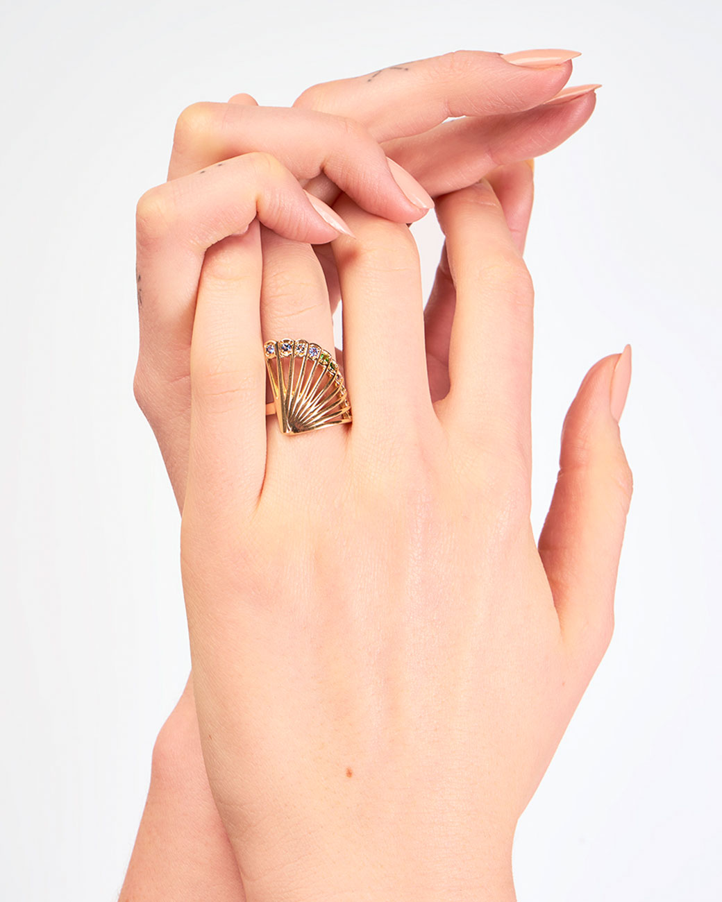 A yellow gold ring in the shape of a fan with diamonds along the top edge. Shown from the front on a hand.