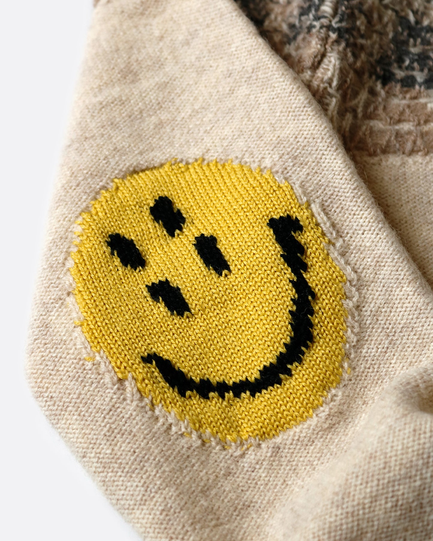 A close up of the smiley patch on the elbow of a sweater.