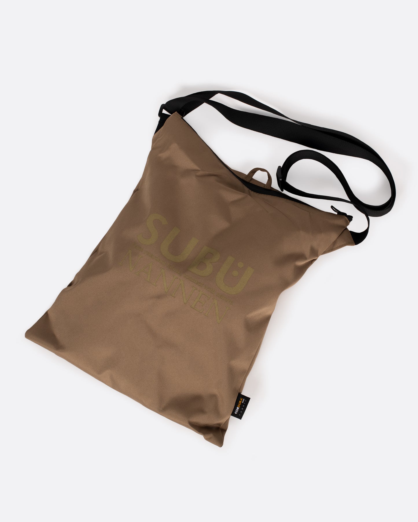 A tan nylon bag with a black strap that is used to carry slippers. Shown from the front.