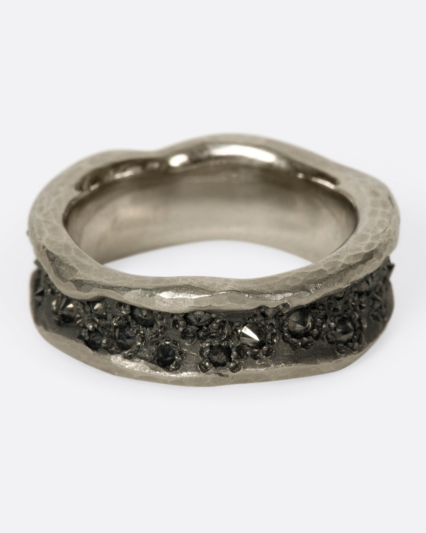 A concave, hammered palladium band with inverted black diamonds throughout its center.