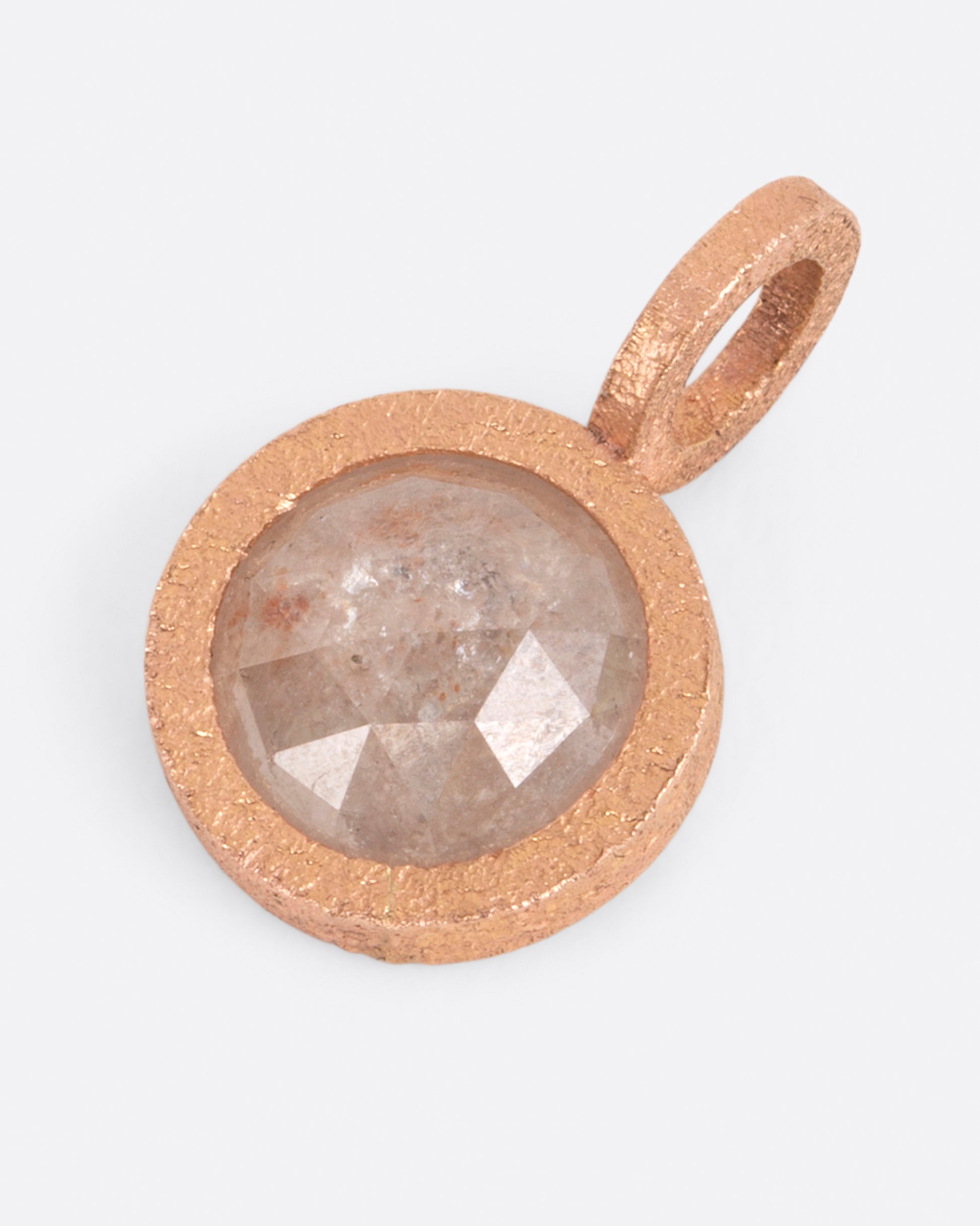 A pendant with a round icy gray diamond set in rose gold. Shown lying flat from the front.