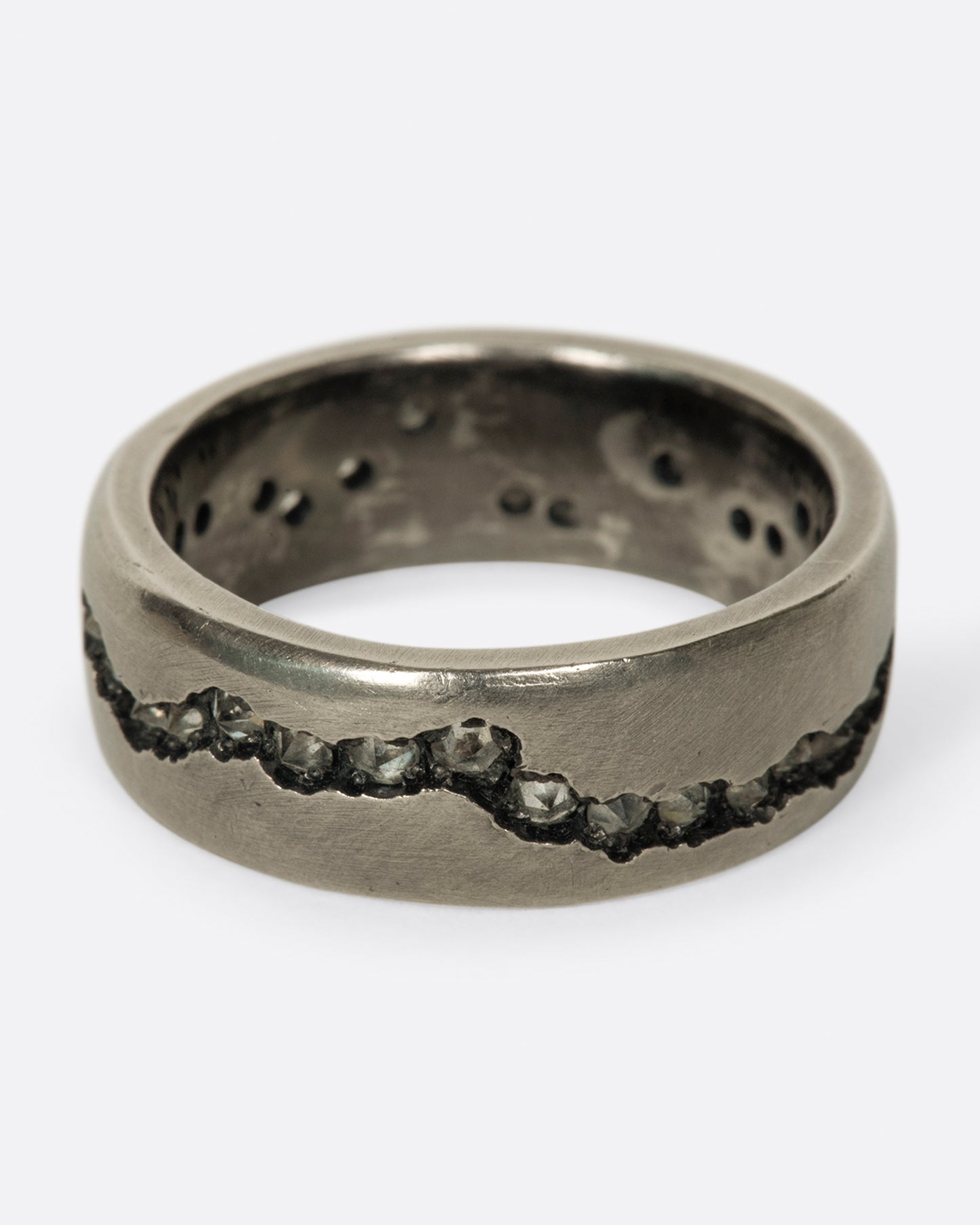 A wide palladium band with inverted diamonds set in a hand cut fissure through the center of the ring. Shown from the front.