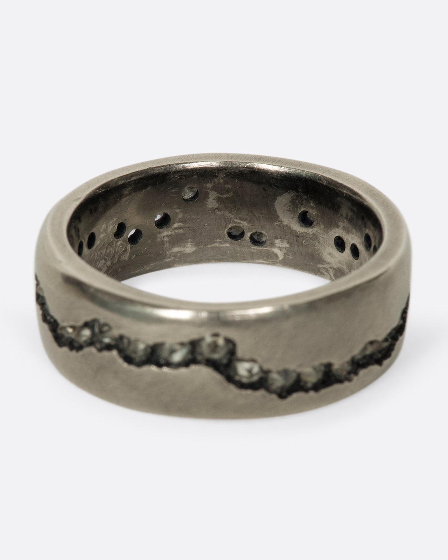 A wide palladium band with inverted diamonds set in a hand cut fissure through the center of the ring. Shown from the back.