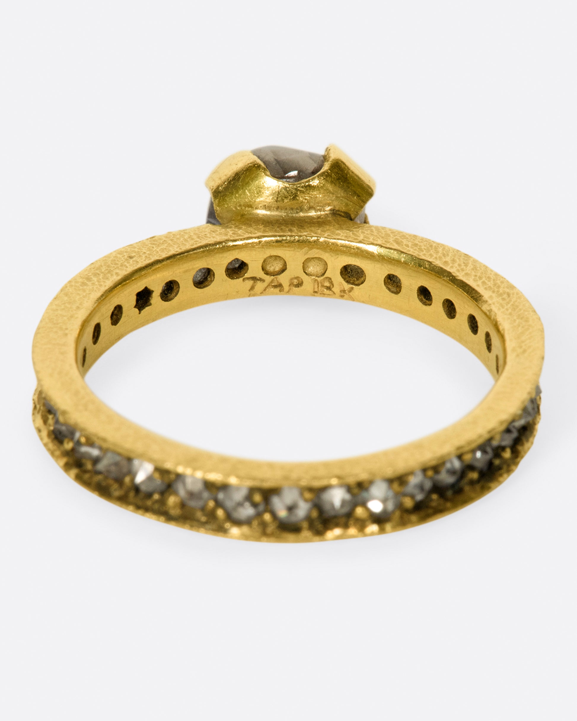 A yellow gold eternity band with inverted diamonds, crowned by a prong set raw yellow diamond. Shown from the back.