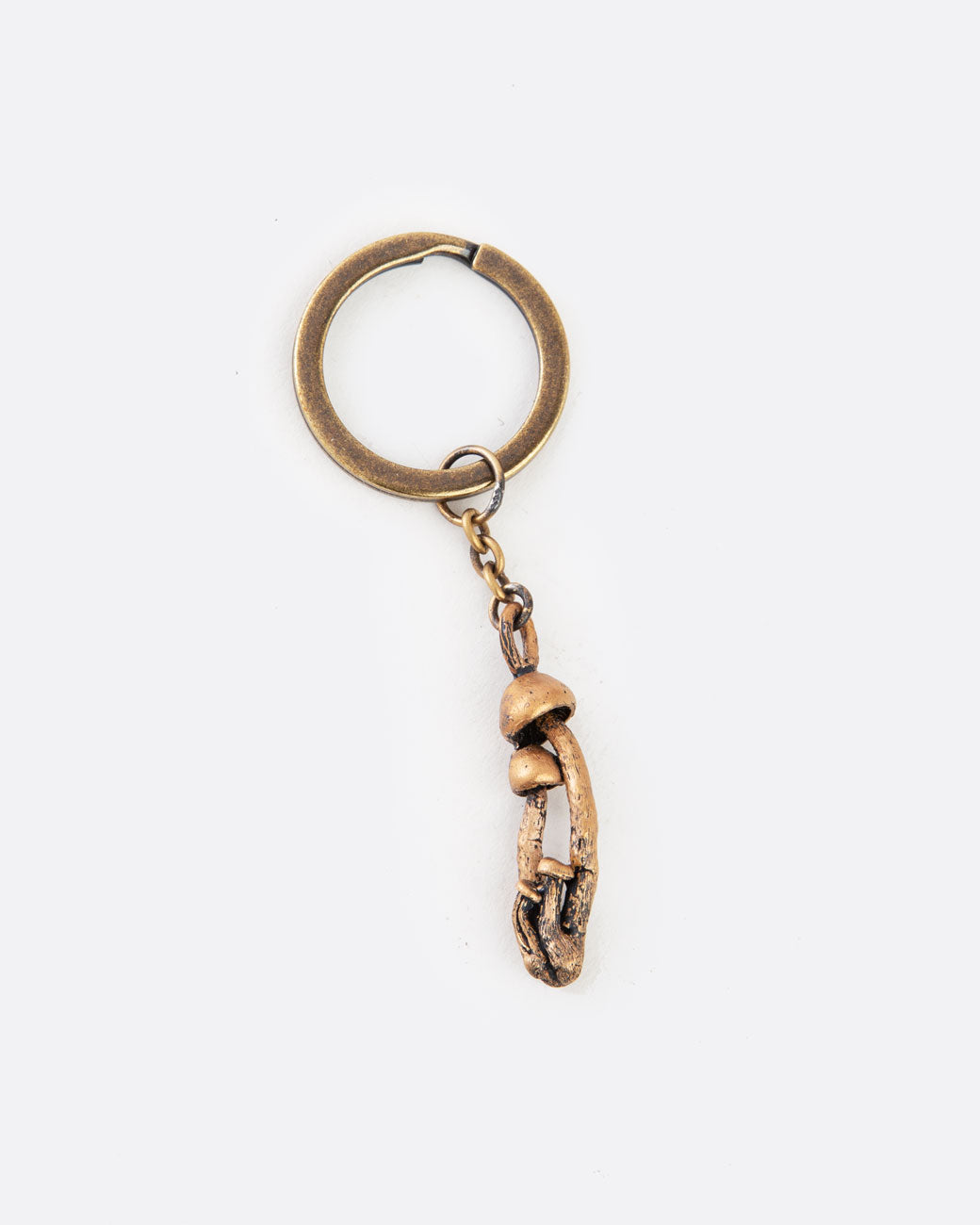 A bronze keychain with a cluster of mushrooms. Shown lying flat from the front.