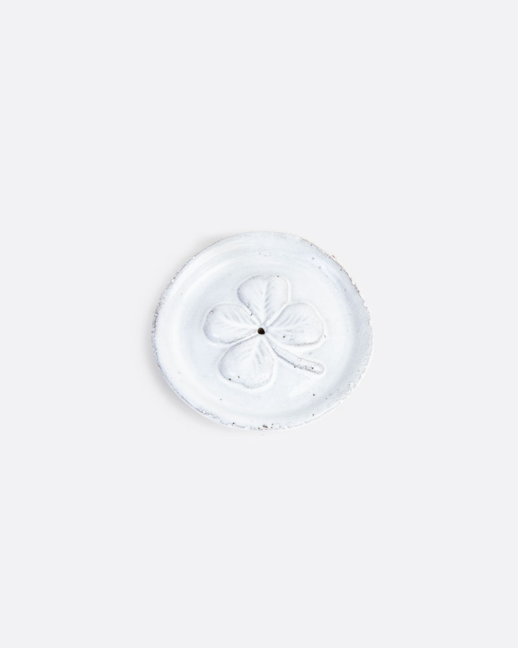 A round white incense burner with a four leaf clover pattern at the center and a whole in the center. Shown from the top.