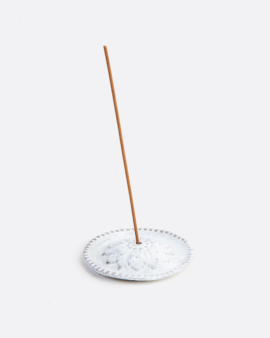 white incense holder with an incense stick in it.