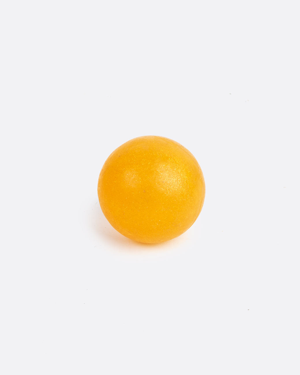 A golden- orange colored round sphere soap. Shown from the front.
