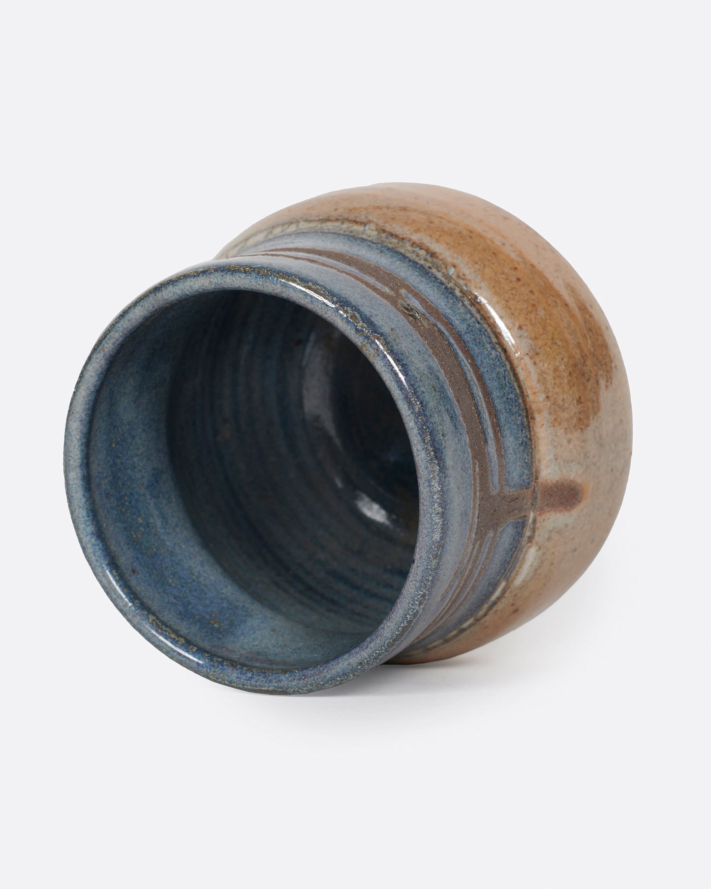 A short, round vase that's glazed half blue and half brown.